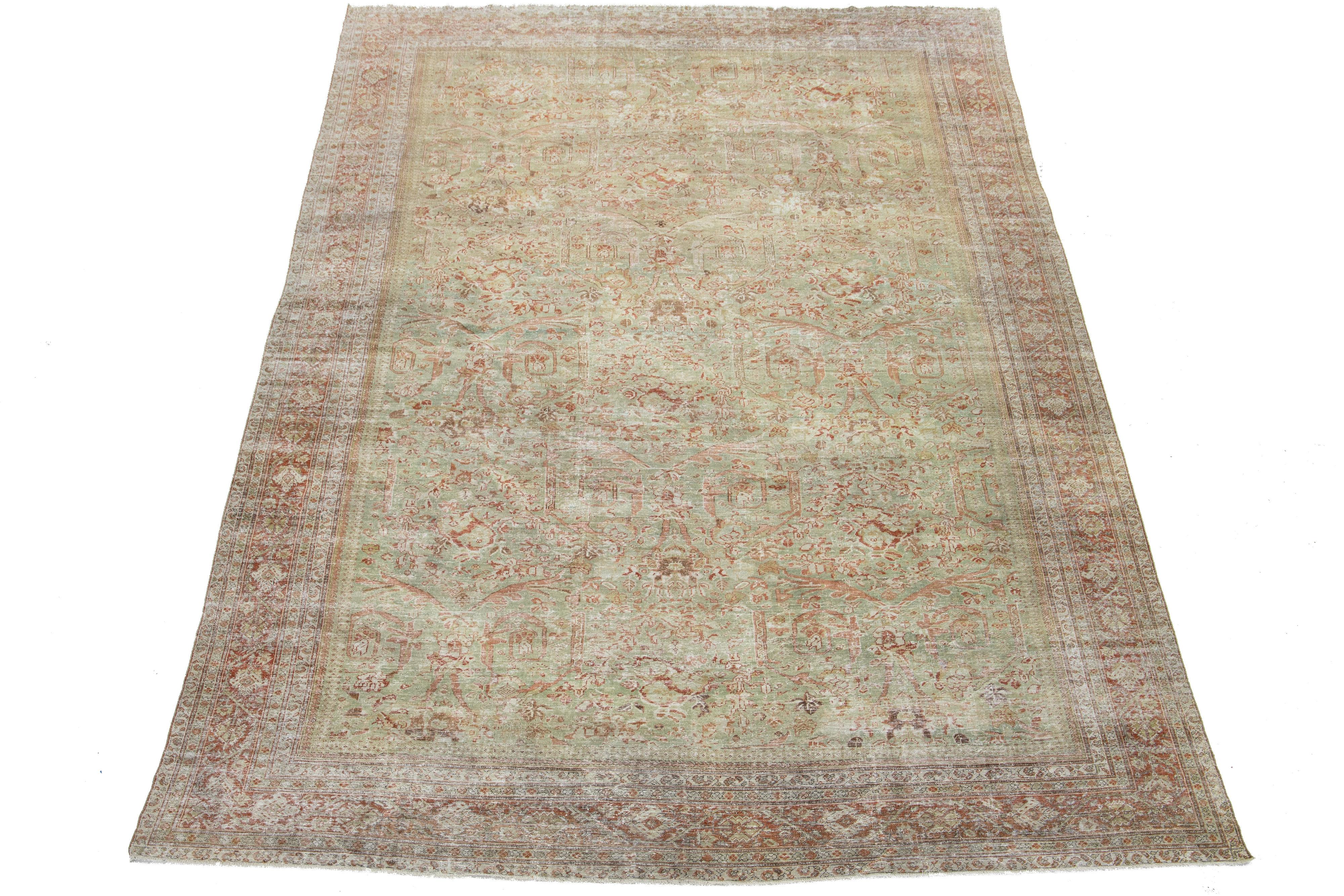 Découvrez le charme exquis de ce tapis antique Mahal en laine nouée à la main et vieillie. Son champ vert captivant présente un motif complexe sur toute sa surface, magnifiquement accentué par des teintes chaudes de rouille et de tan. Ce tapis n'est