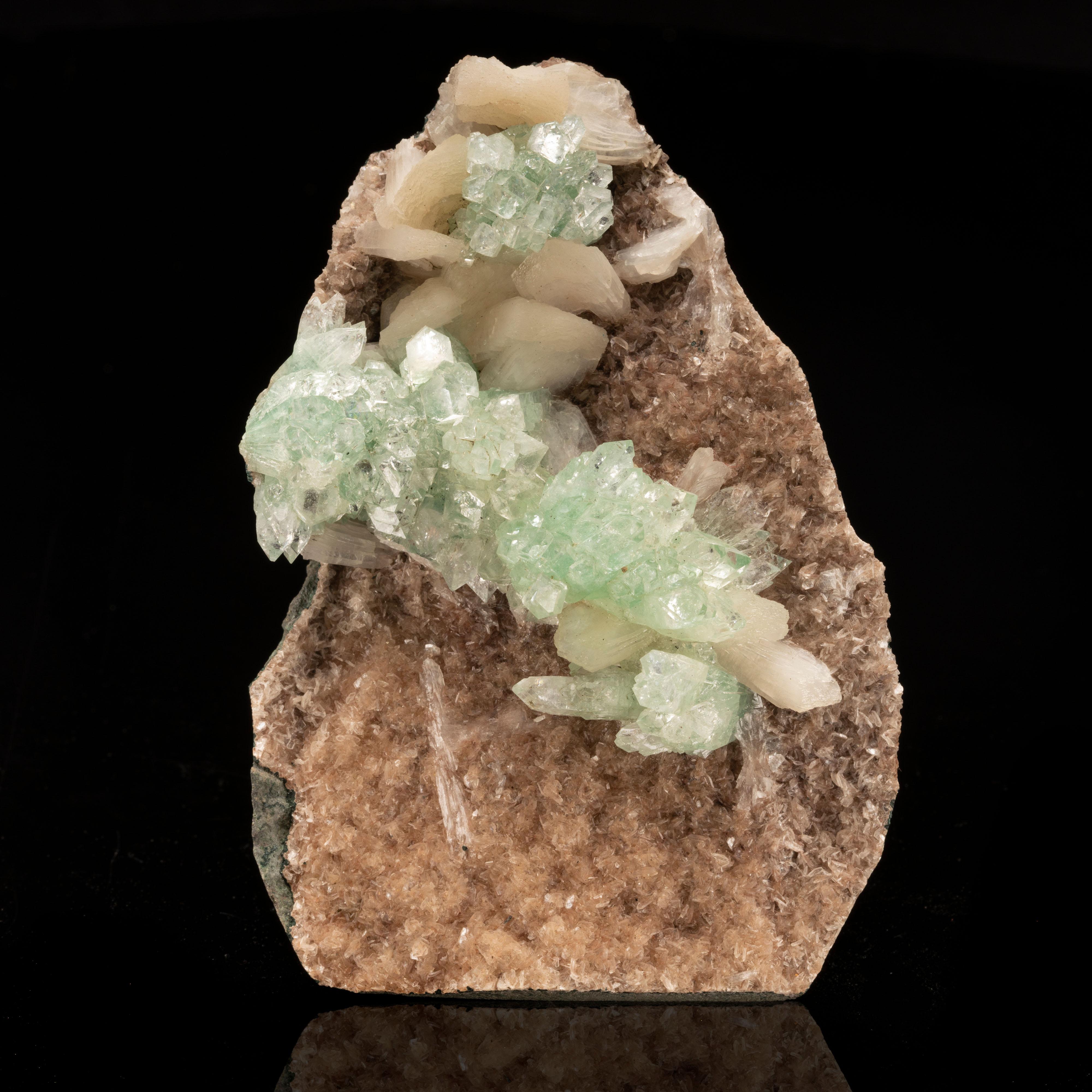 This unique specimen from India features a red heulandite matrix and a glistening sash of gorgeously refractive and lustrous, perfectly crystallized green apophyllite accented with waxy peach stilbite. An aesthetically special piece chock-full of