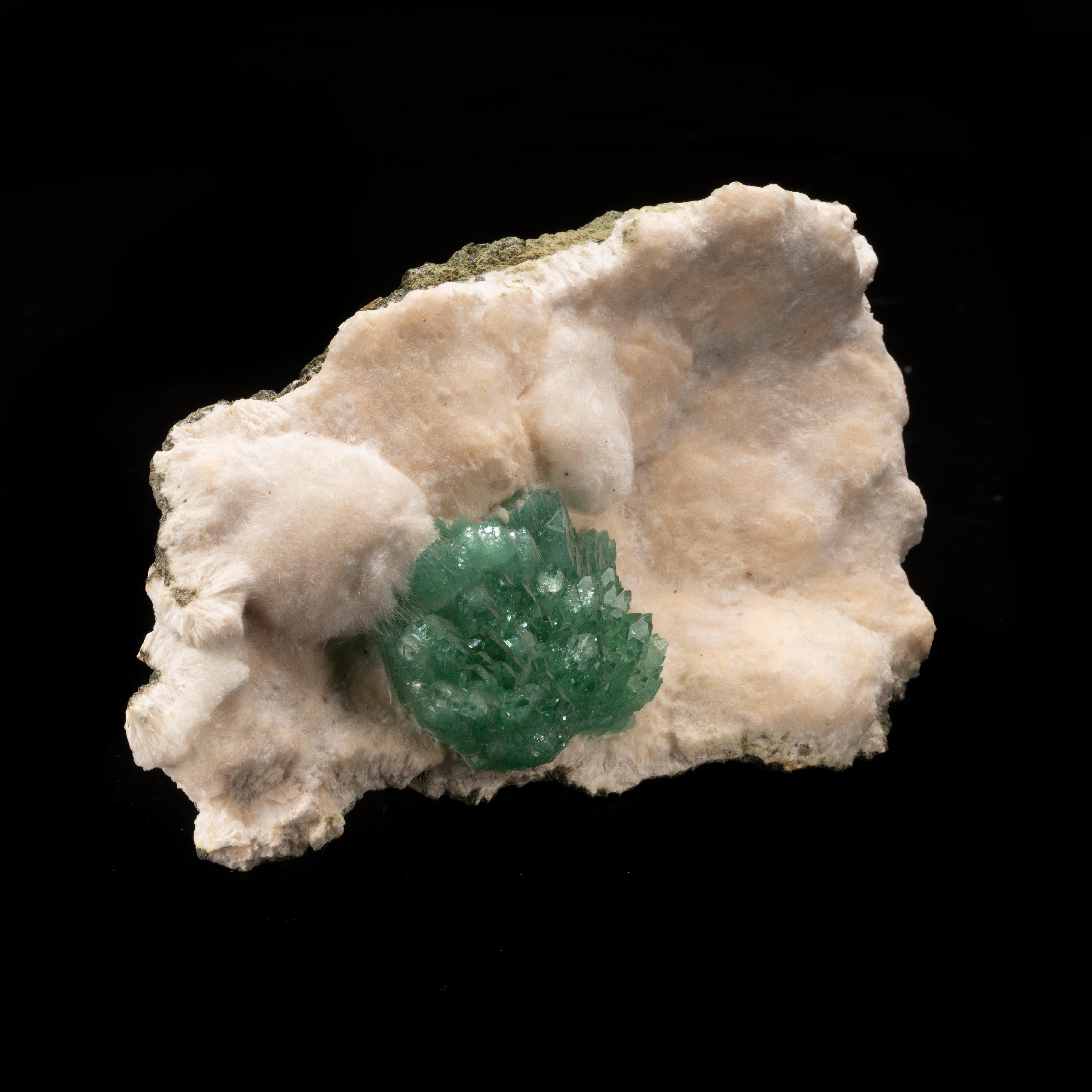 Cette grappe d'apophyllite d'un vert profond, remarquablement arrangée, a une grande présentation naturelle sur un lit doux et lustré d'okenite, un minéral rare souvent associé aux minéraux zéolitiques. L'okenite a un comportement cristallin
