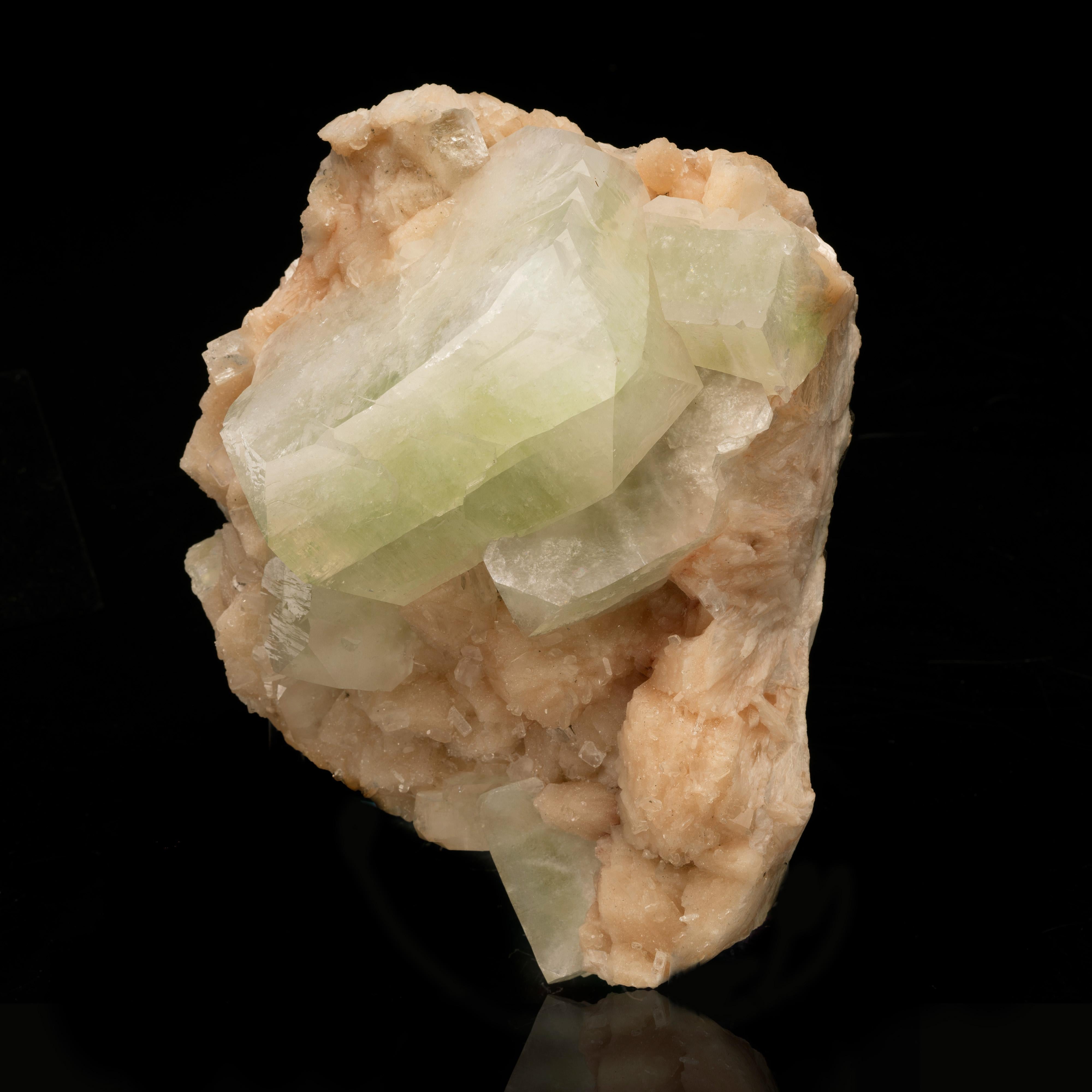 This large and textural piece features huge, gemmy, gorgeously formed green apophyllite crystals growing on an abundance of lustrous, beautifully pigmented peach stilbite. This large cabinet sized specimen out of India is sure to add fascination to