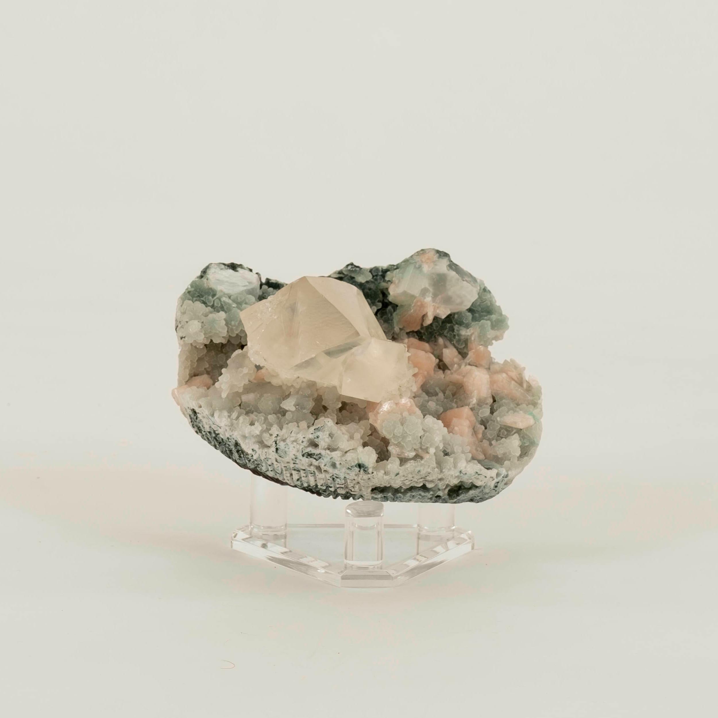 Spécimen minéral d'apophyllite verte, de stilbite et de calcédoine sur un support en lucite. Les dimensions sont celles du spécimen sur le support. 