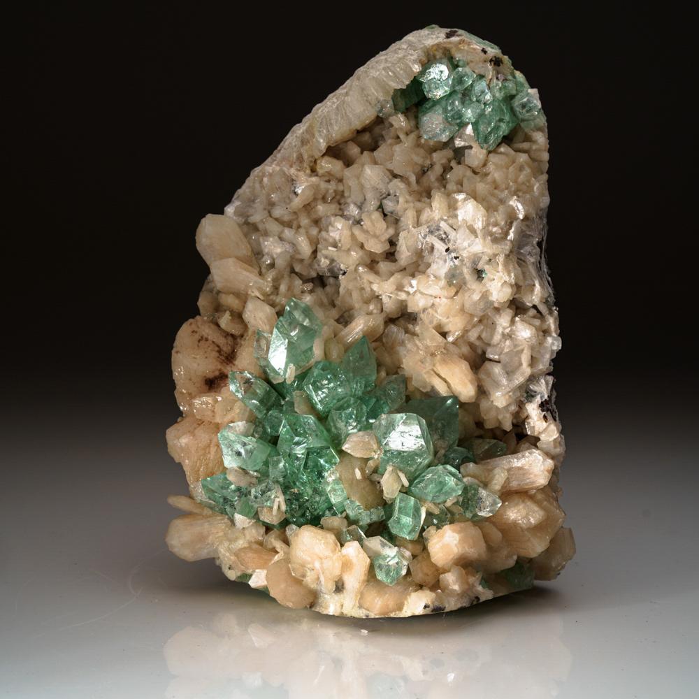 From Pashan Hill Quarry, Pune District, Maharashtra, India

Sparkling cluster of green apophyllite crystals in a radiating formation on matrix lined with creme-colored stilbite crystals in aggregates. The apophyllite crystals are fully terminated