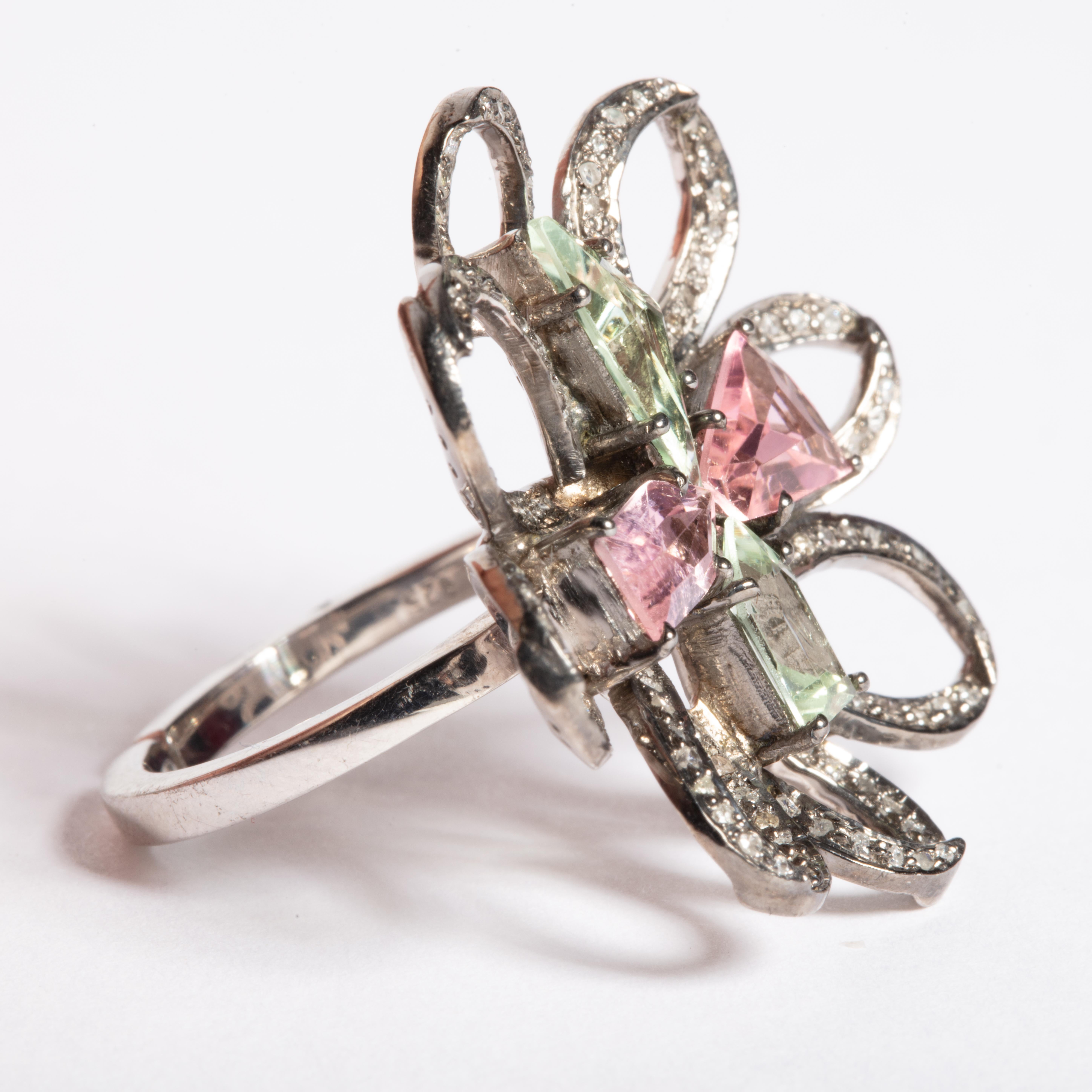 Unusually cut and faceted green aquamarine and morganite stones create the center of this flower ring.  The petals are brilliant cut and pave' set diamonds set in an oxidized sterling silver.  Ring size is 7.25.