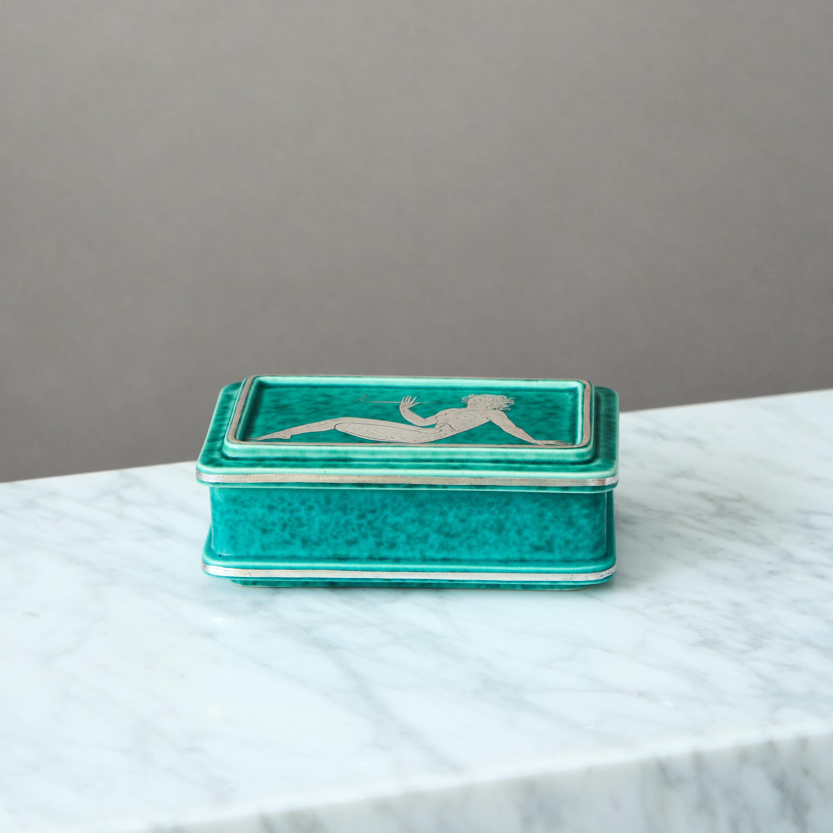 A beautiful and rare Art Deco / Swedish Grace stoneware lidded box with amazing green glaze and hand-painted sterling silver decor, hence the name 'Argenta'.
Made by Wilhelm Kåge at Gustavsberg in Sweden, 1930s. 

Good condition, with som scratches