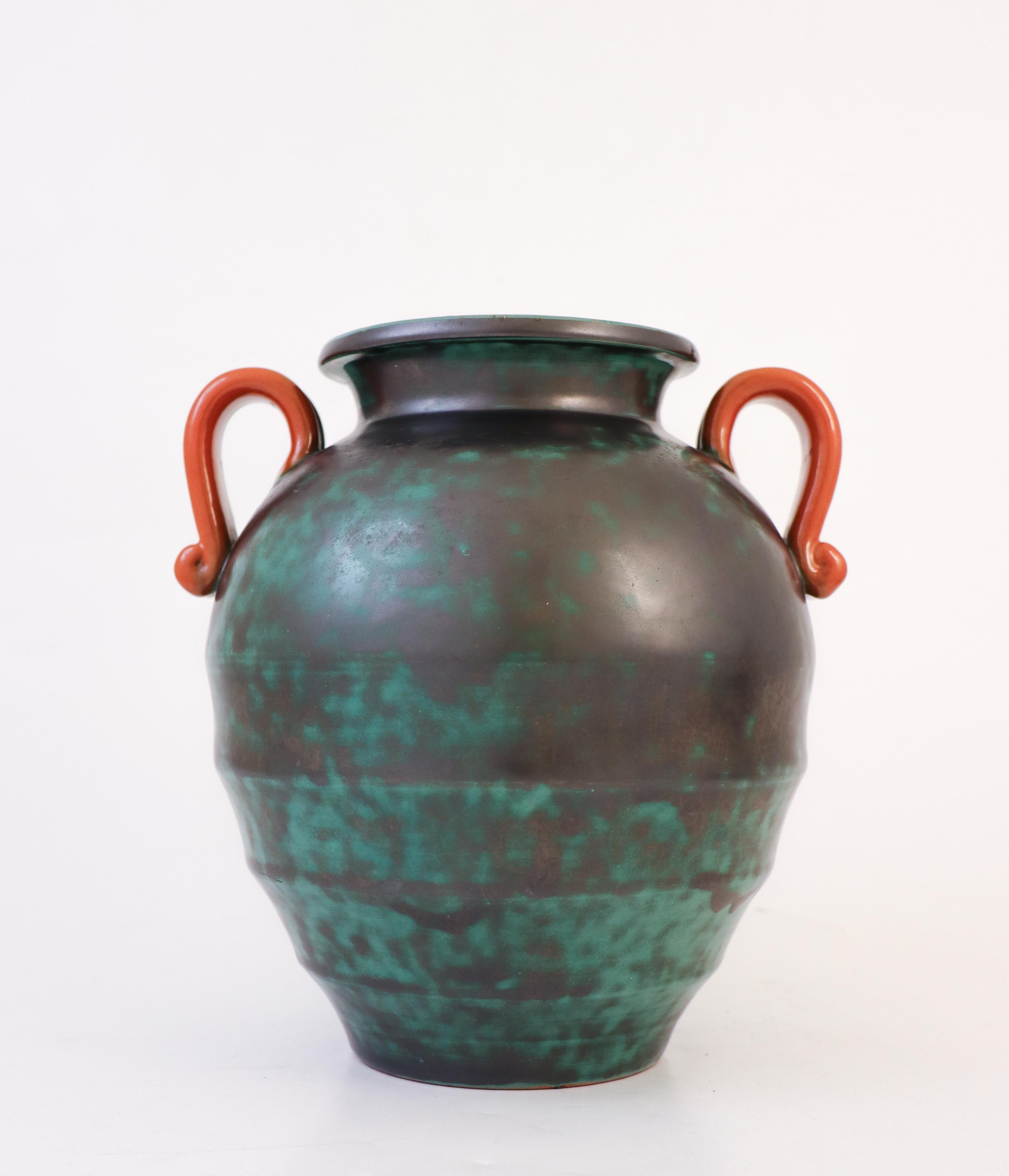 Un magnifique vase en céramique verte avec des poignées orange en forme d'urne romaine classique, le vase est conçu par Harald Östergren à Upsala Ekeby entre 1937-1938. Il mesure 21 cm de haut et environ 17 cm de diamètre. Il est en excellent état.