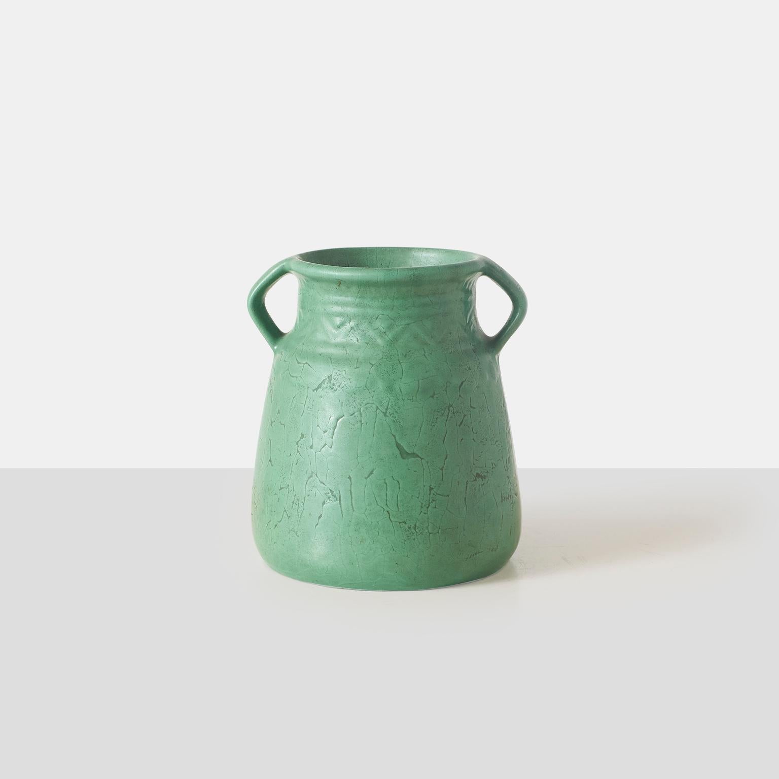 A matte green Arts and Crafts pottery vase with two handles and subtle geometric decoration. Unsigned.