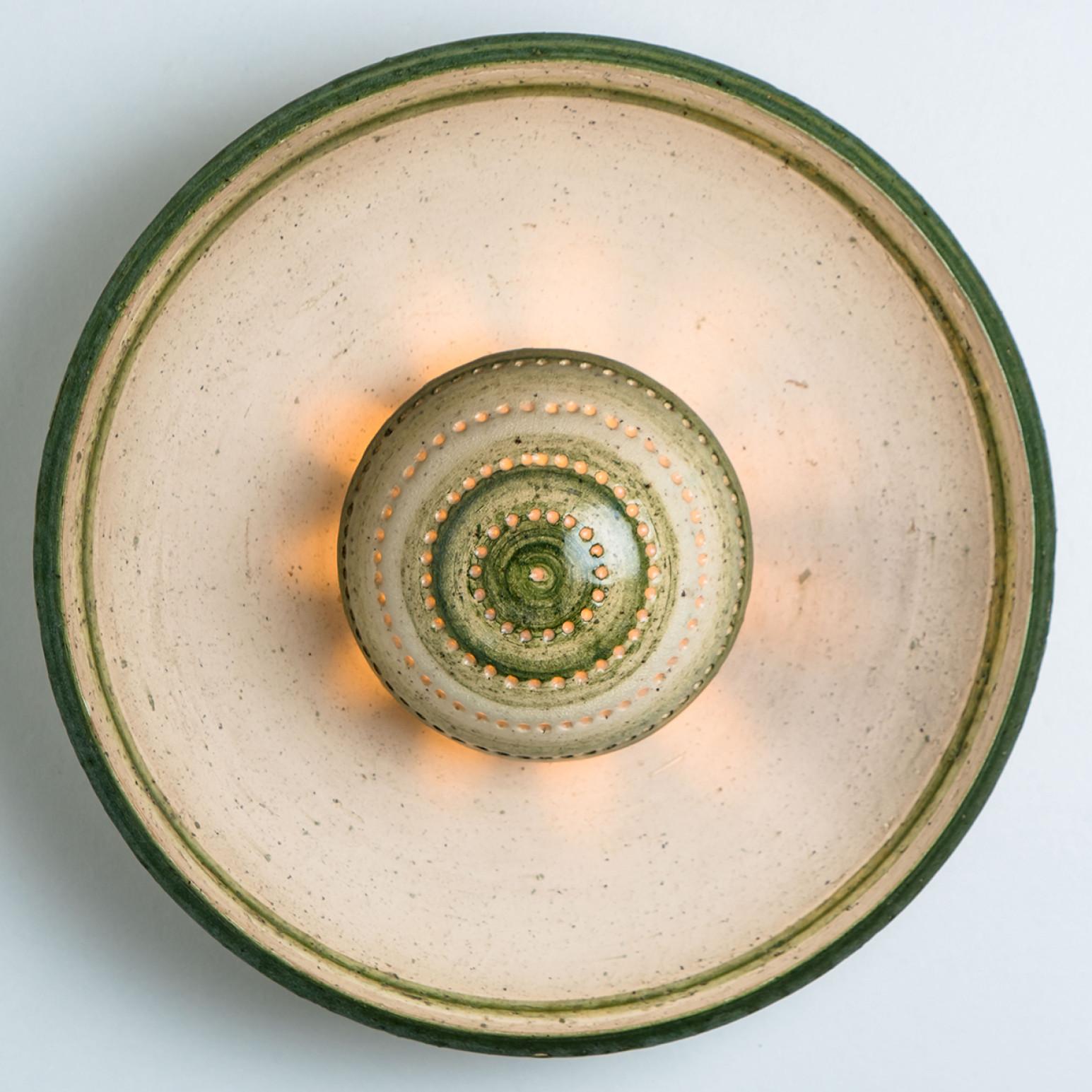 Stunning round wall lamp with an unusual shape, made with rich colored green ceramics and a mushroom-like centre, manufactured in the 1970s in Denmark.

Dimensions:
Diameter: 10.23