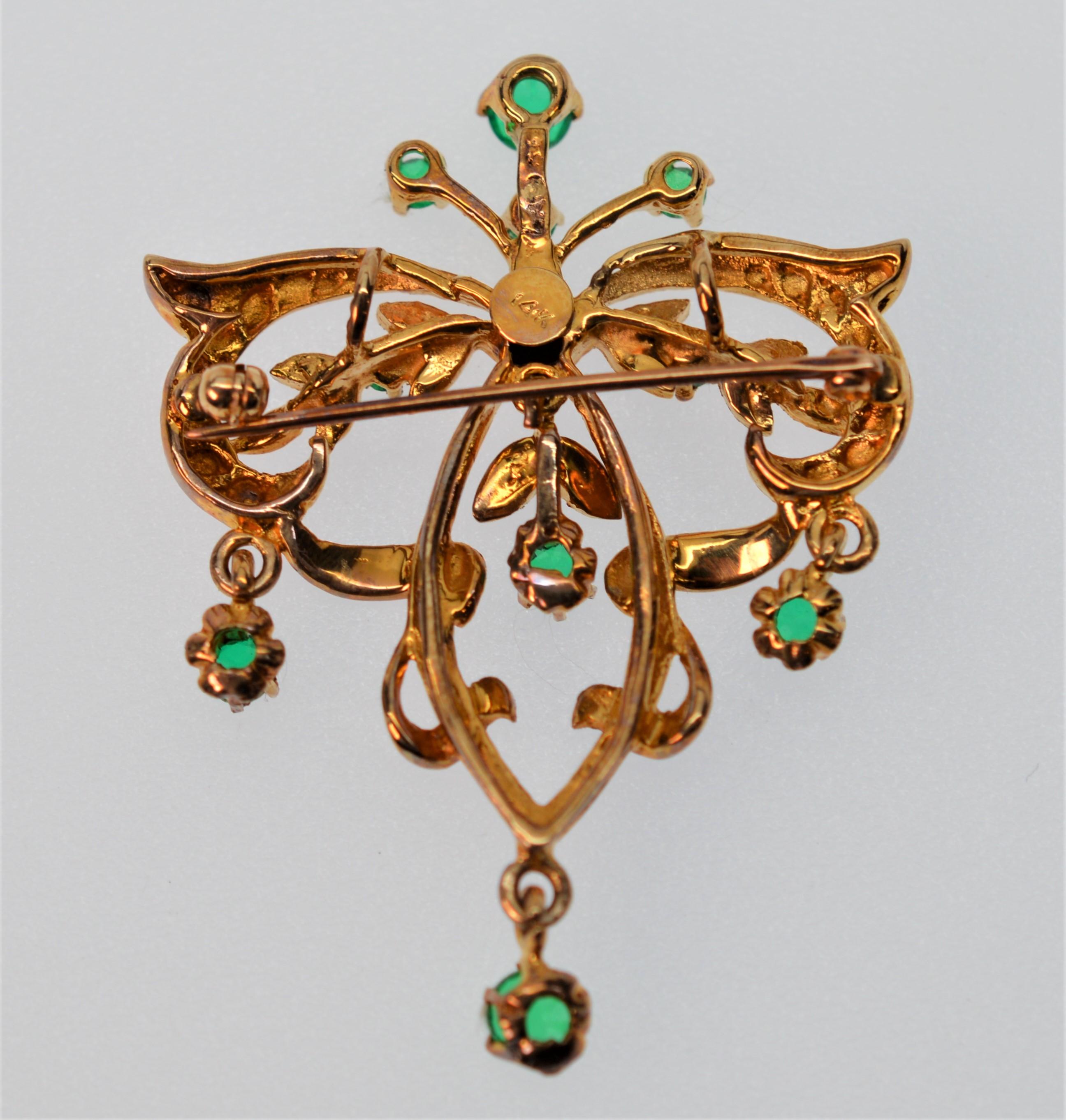 This antique style piece can be worn as a pin or pendant. Made of fourteen karat (14K) satin yellow gold, with a vintage look and style. The vivid green beryl doublets give a rich, classic look and the dangling stones give movement and life to the