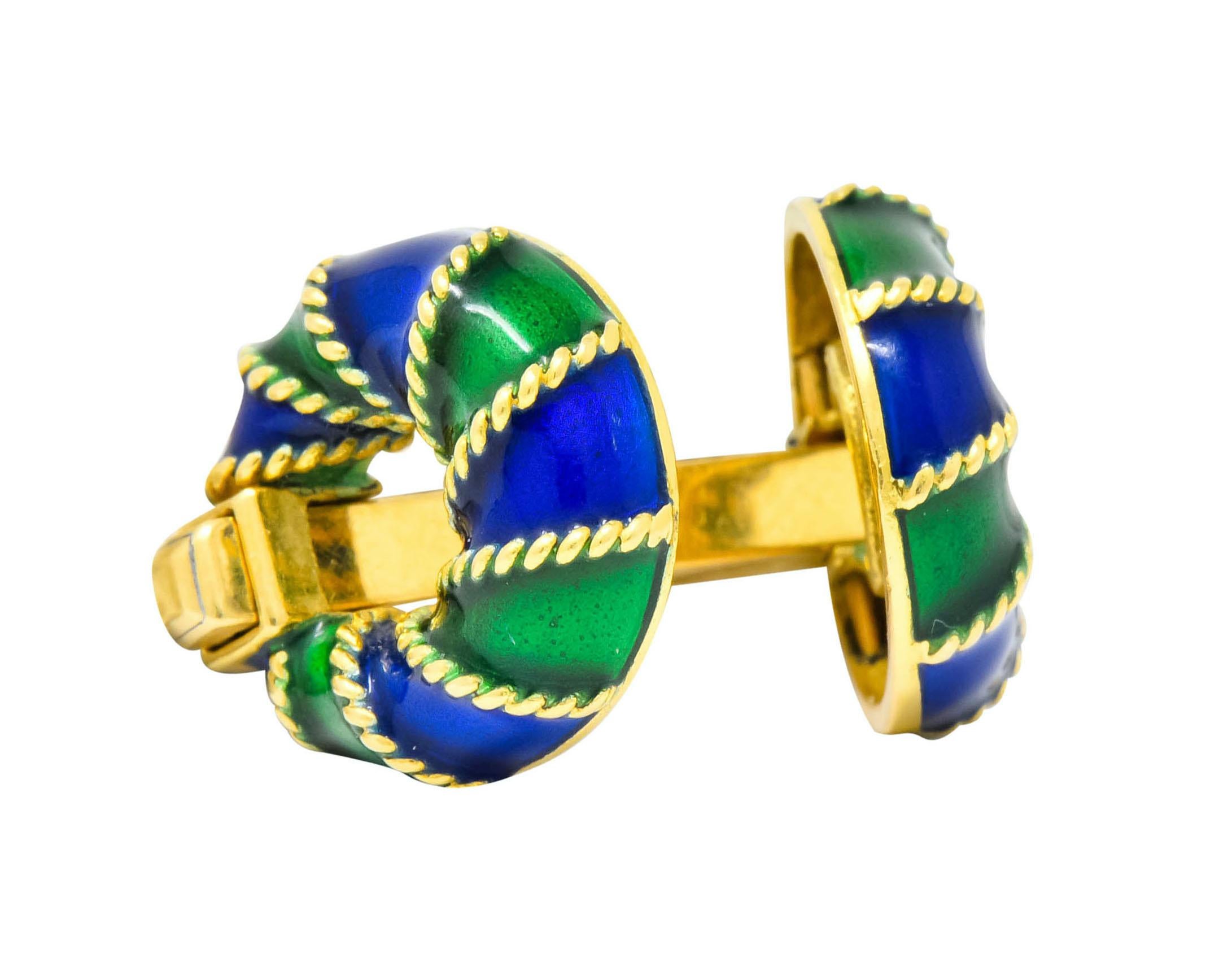 Cufflinks designed as gold bar terminating in two tori accented by a twisted cable motif throughout

With alternating green and blue enamel, exhibiting no loss

Completed by sliding, spring-loaded mechanism

Tested as 18 karat gold

Circa