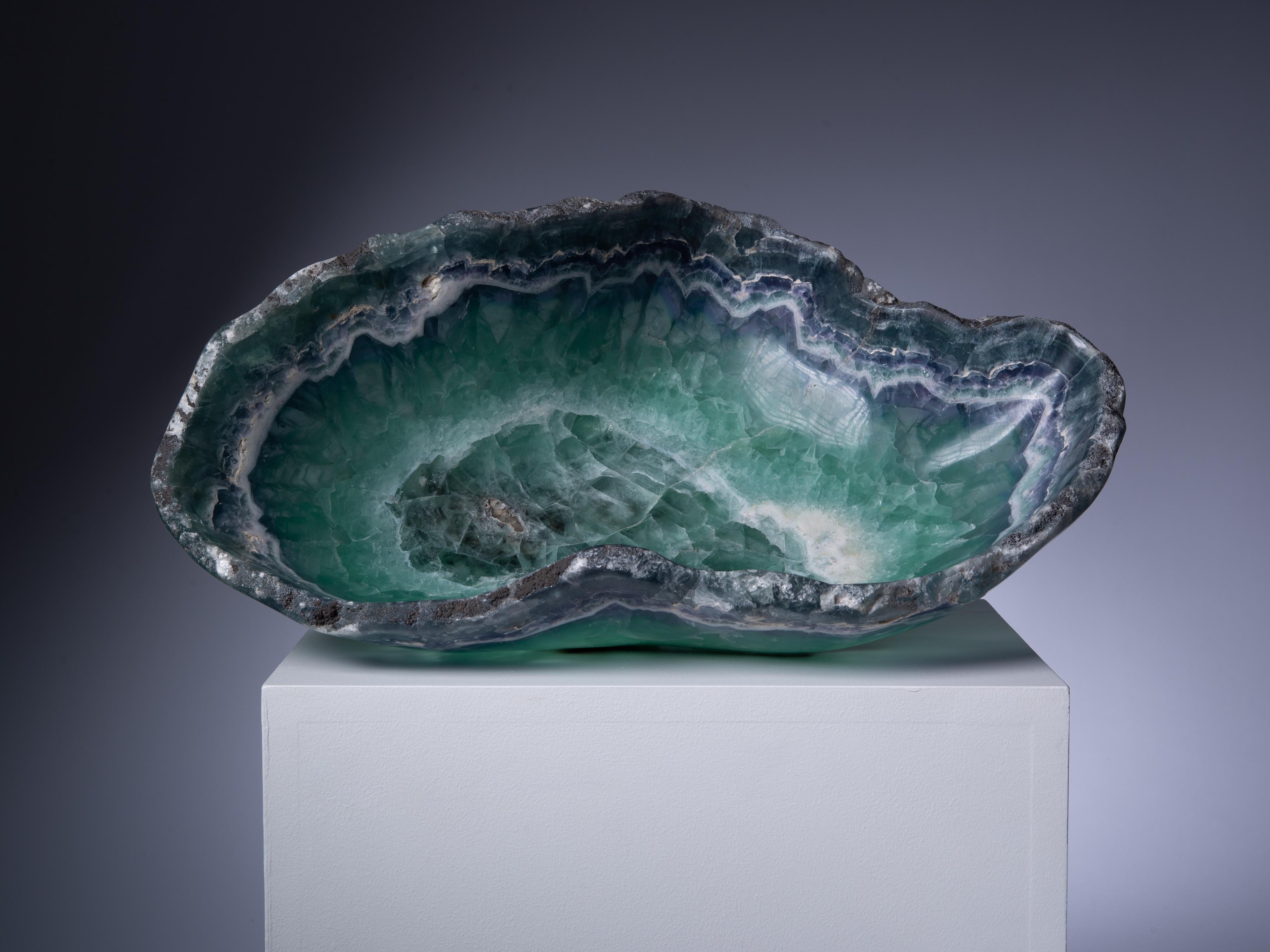 A gorgeous green-blue bowl carved from a single block of Mexican fluorite. The bowl has been beautifully contoured along the bands of the dark blue fluorite, with their attractive angular crystals visible in cross-section.

This piece was legally