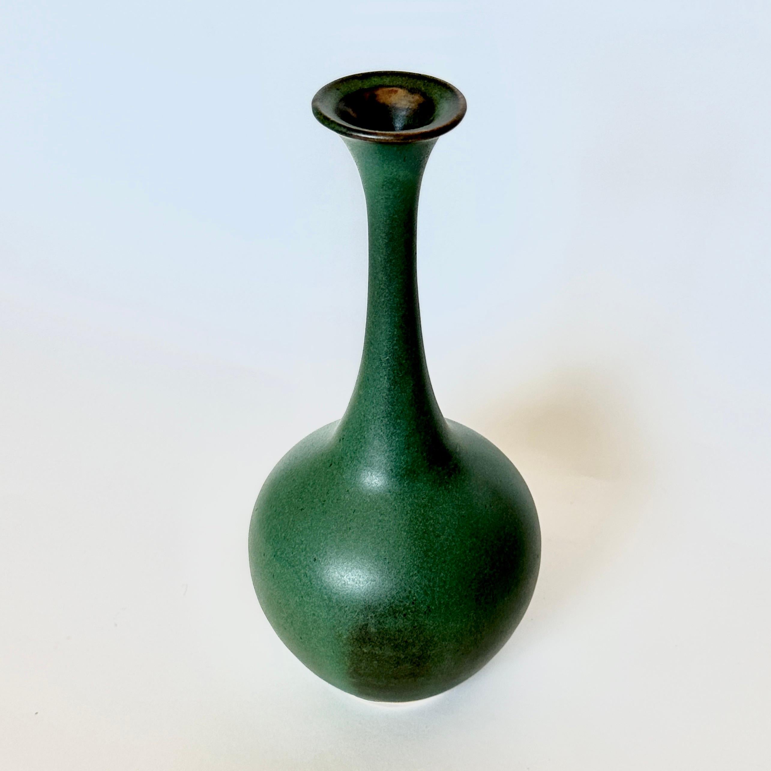 Wheel-thrown and hand-shaped tall bottleneck vessel with flared wide mouth made by Dana Chieco. Glazed in dark green with bronze tones. Fired to Cone 10 (2345 degrees Fahrenheit). 

By accentuating curves and playing with unexpected proportions,