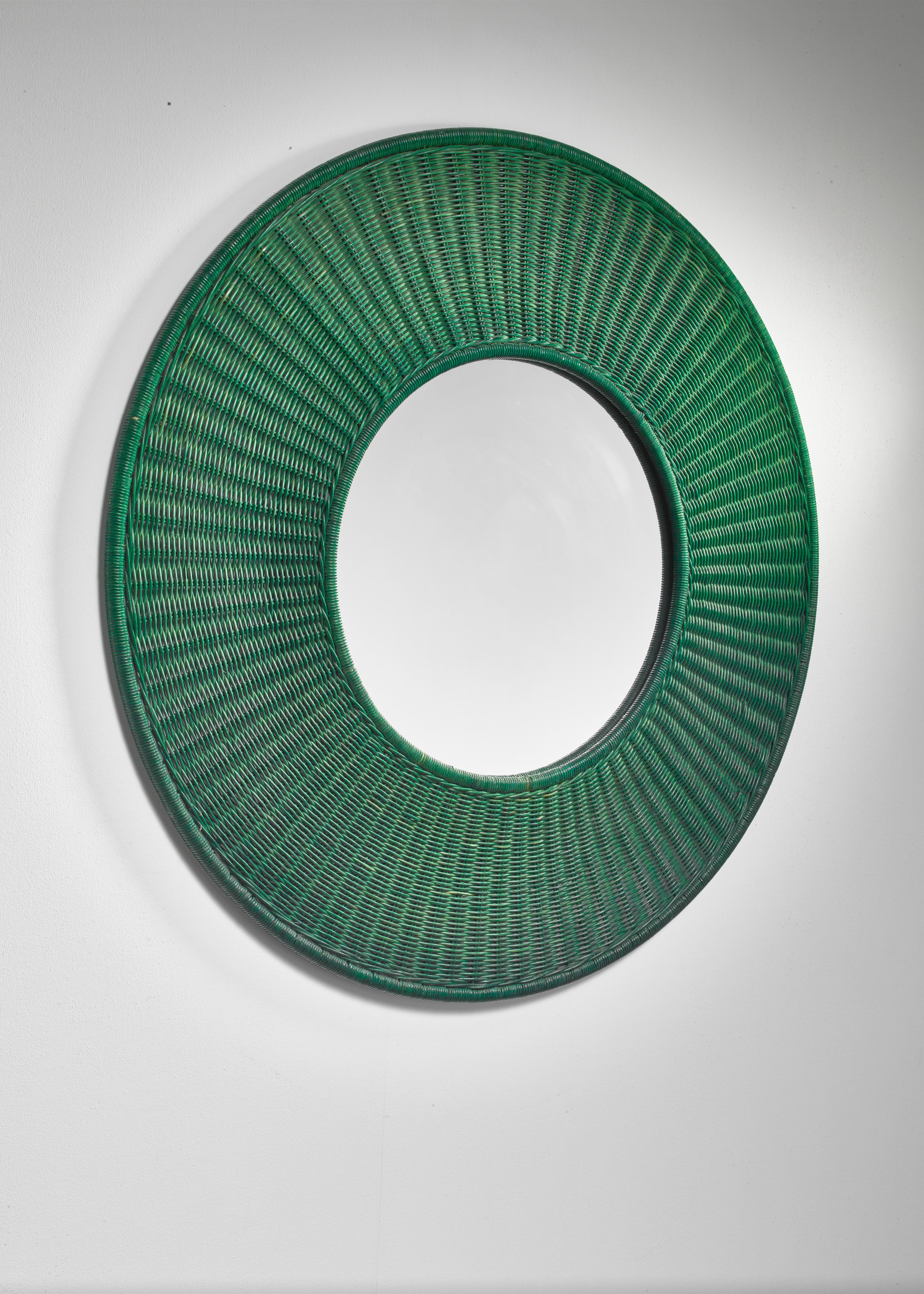 A large wall mirror with a round, green woven cane frame.