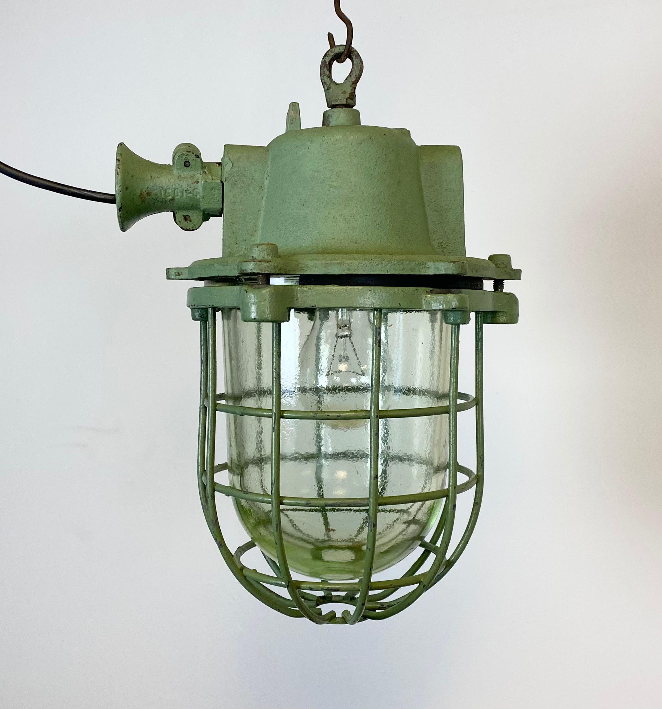 Industrial hanging lamp manufactured during the 1960s in former Czechoslovakia. It features cast iron top, clear glass cover and iron grid. Porcelain socket for E 27 lightbulbs and new wire. The weight of the lamp is 8 kg.