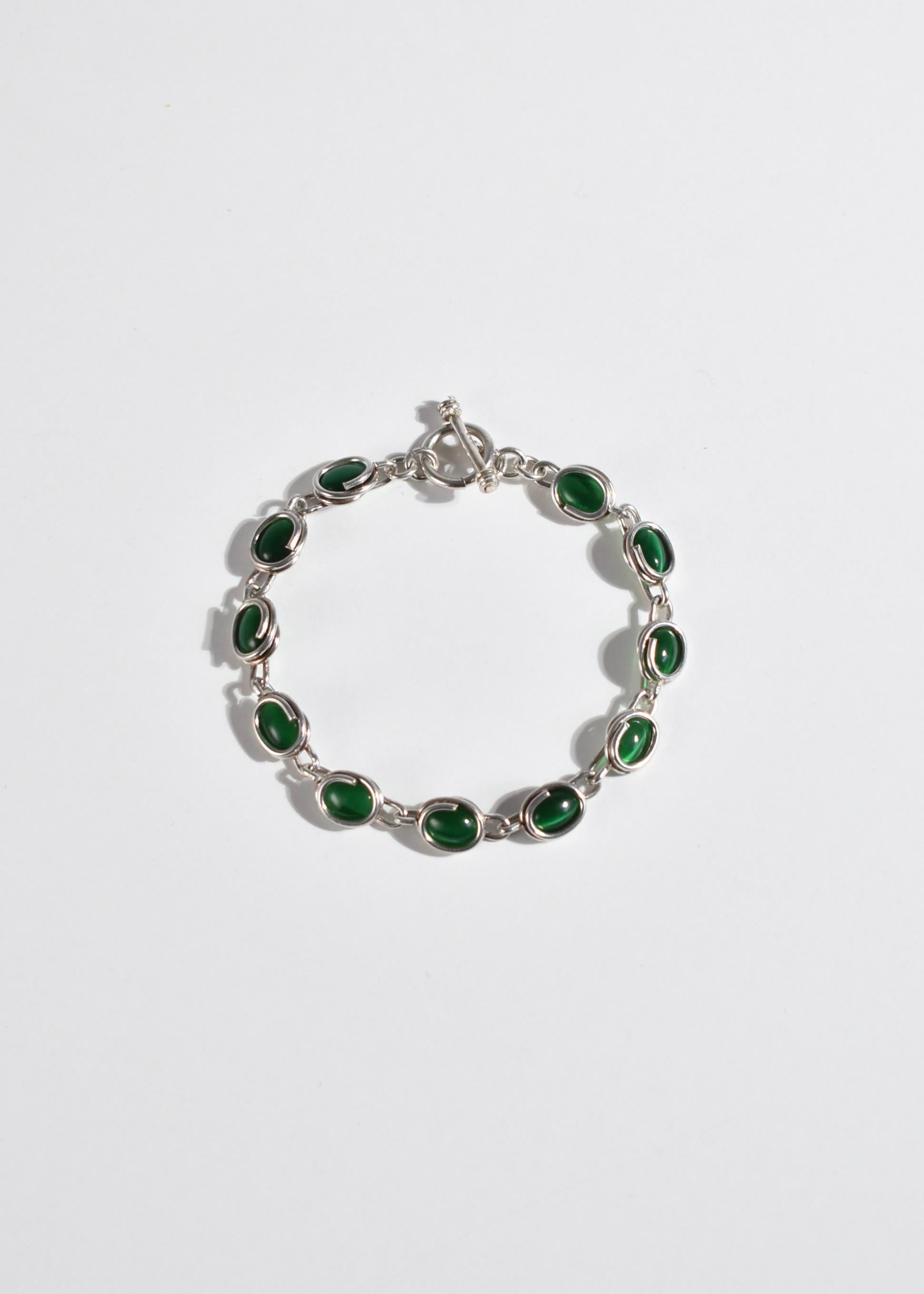 Vintage silver link bracelet with green cat's eye cabochon detail and toggle closure. Stamped 925.

Material: Sterling silver, green cat's eye.