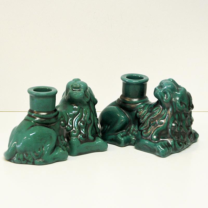 Pair of majestic green lion candlelight figurines in lying position. Holed underneath with stamp from Uppsala, St. Erik. Made of ceramic and glaced. This vintage lion candle light pair would look amazing displayed on a fireplace mantel or book shelf