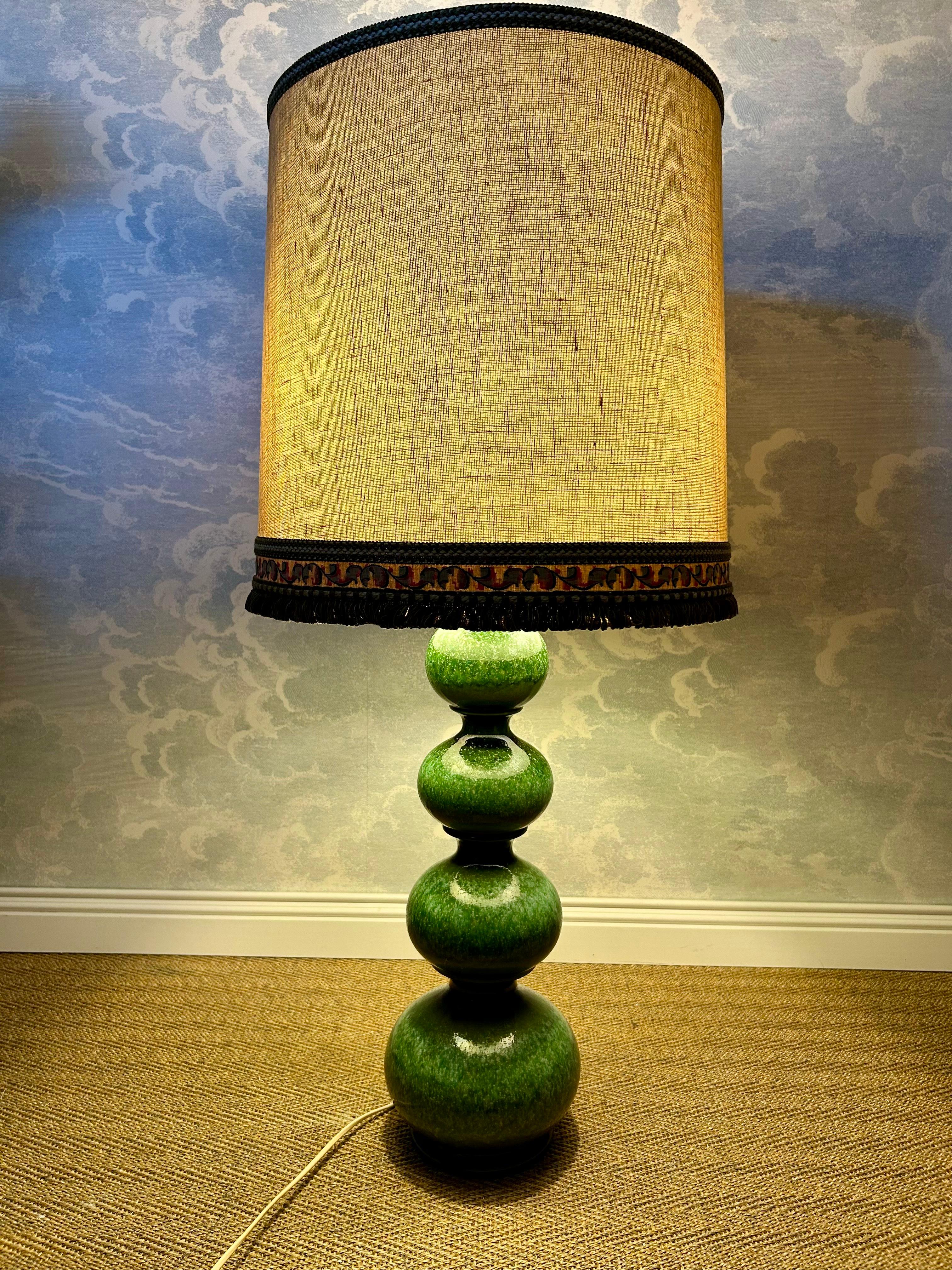 Quattro globi di ceramica smaltata di colore verde foresta riflettono delicatamente la luce emessa da due lampadine E27 orientate verso il basso. Una terza lampadina rivolta verso l'alto in un riflettore metallico può essere accesa separatamente con