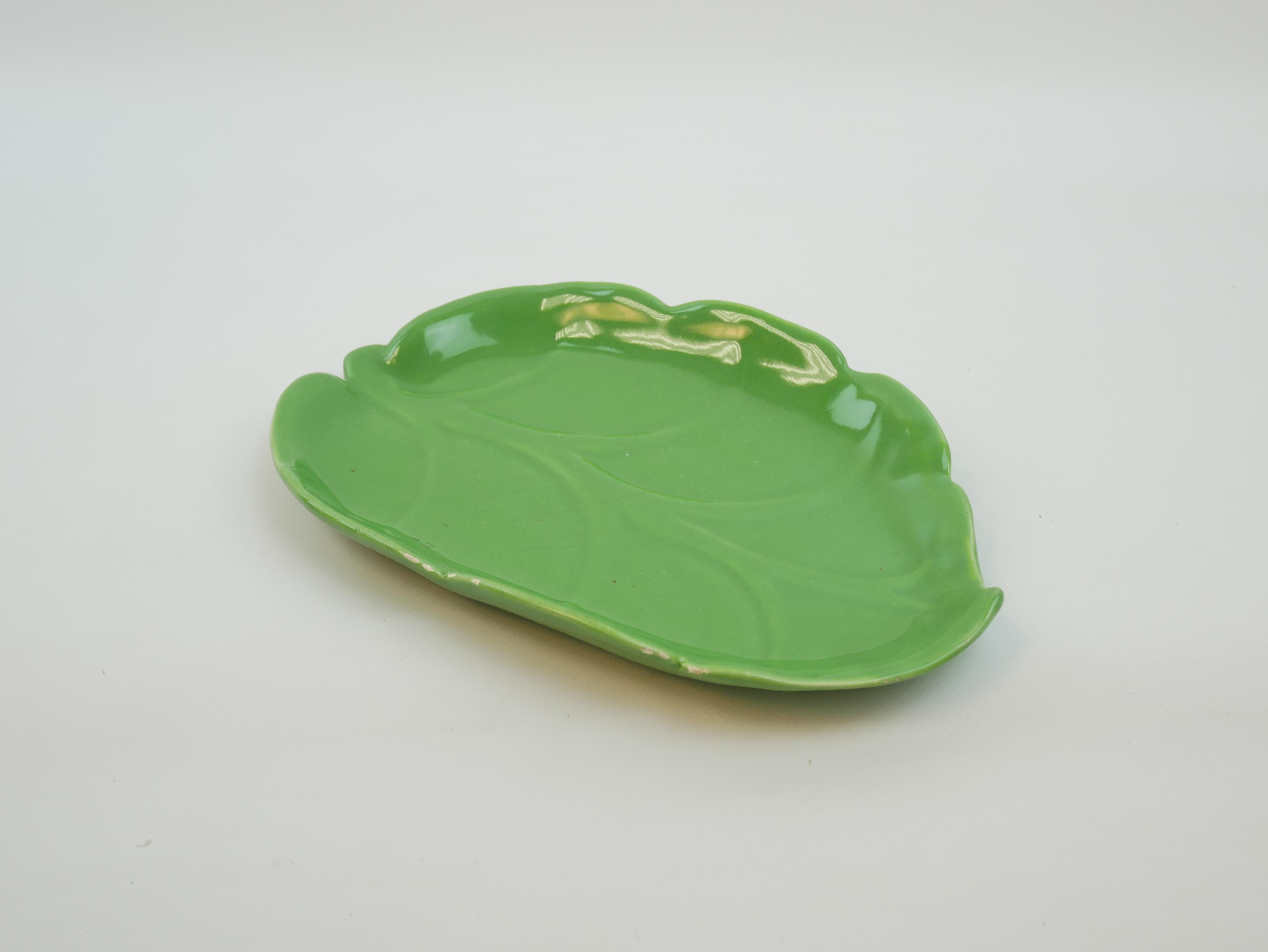 Este plato de cerámica esmaltada de un verde vibrante es un sorprendente ejemplo del arte de Madoura. Con forma de hoja estilizada, capta tanto la elegancia como un toque de capricho. El esmalte brillante resalta las vetas en relieve y los contornos