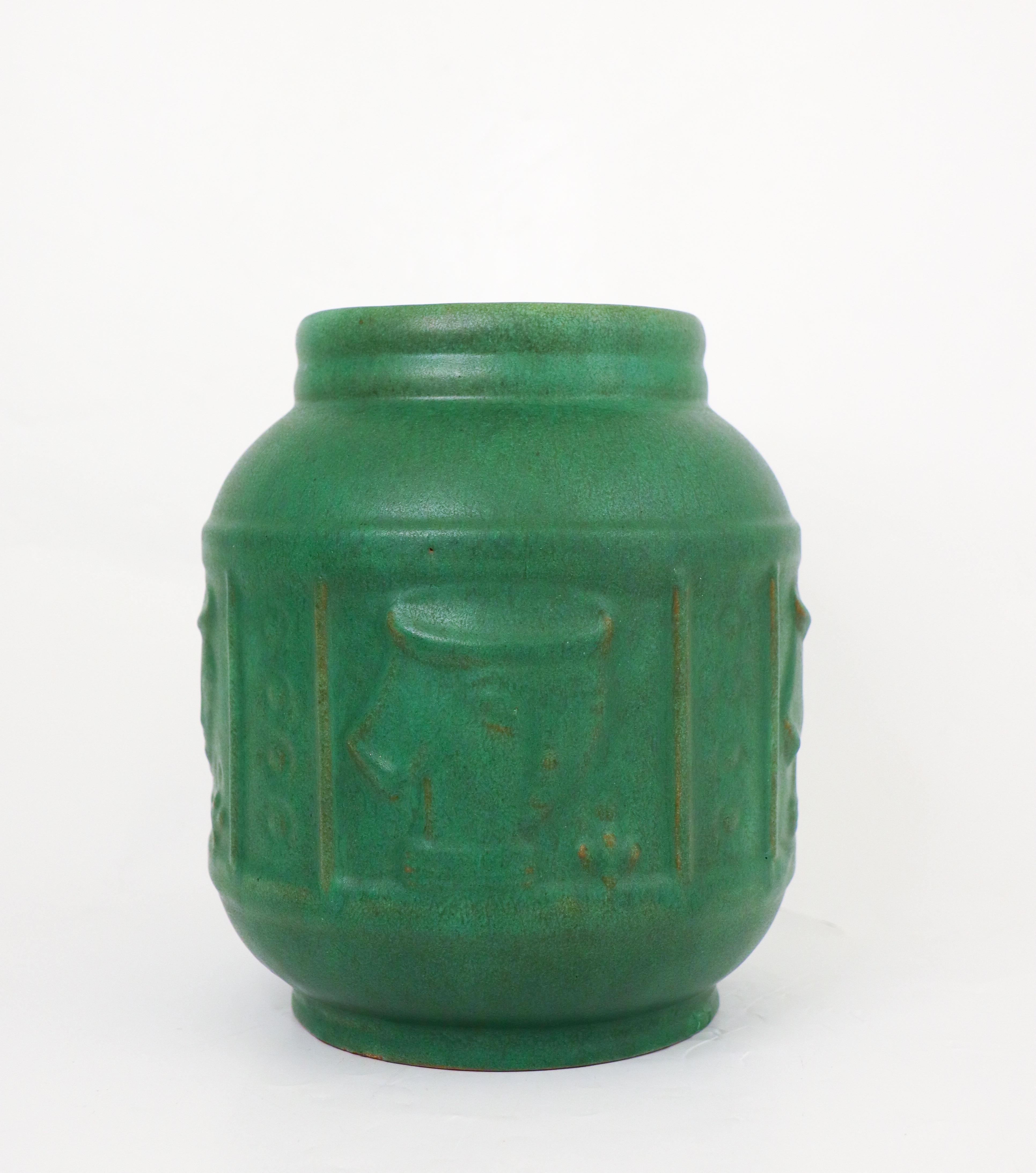A large dark green ceramic vase with faces in relief designed by Kupittaa Savi in Finland. The vase is 21 cm high and in very good condition except from a minor repair on the base and some minor chips near the base. 