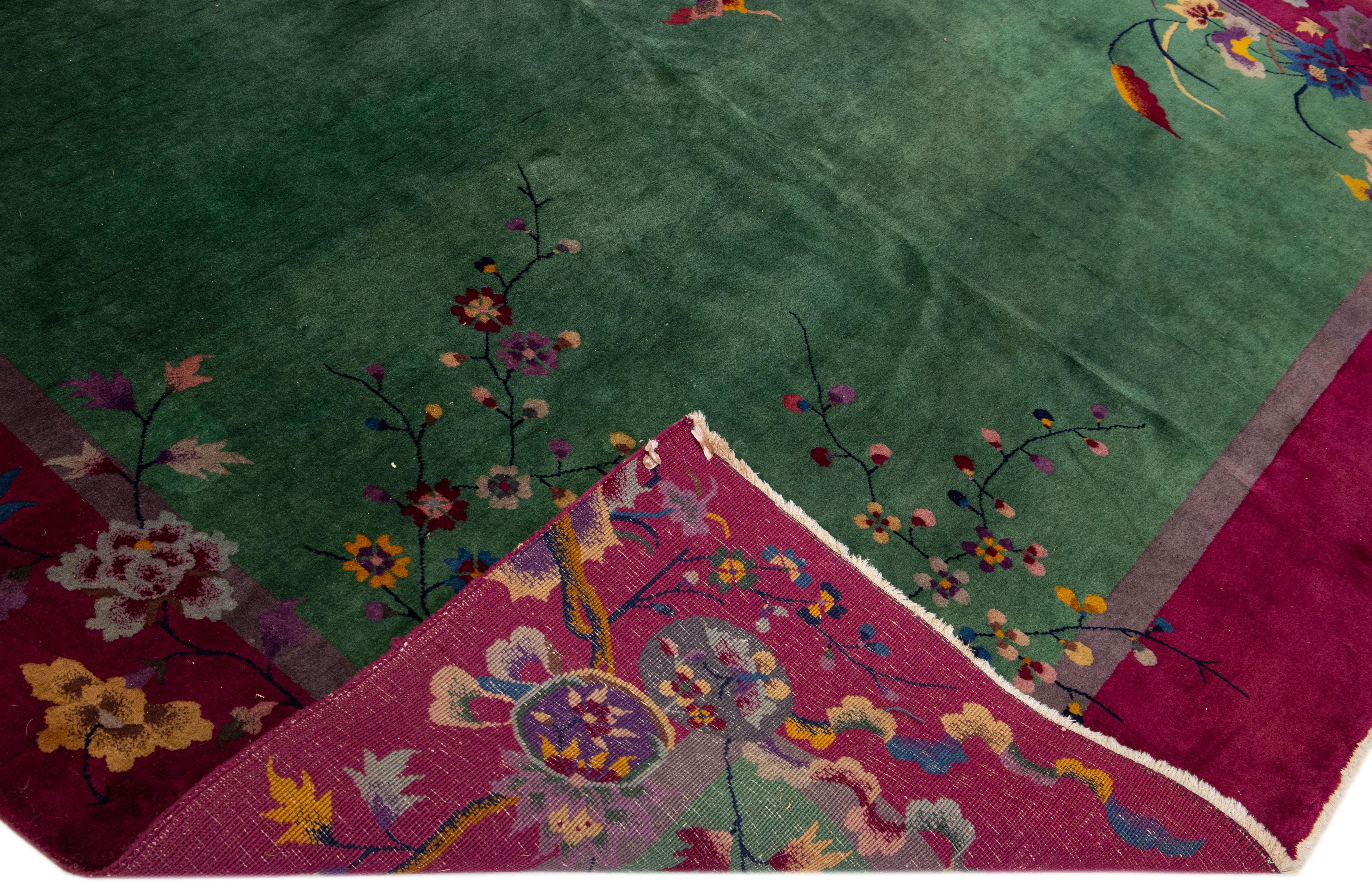 Preciosa alfombra antigua Art Déco de lana anudada a mano con un campo verde. Esta pieza tiene un marco rojo con detalles multicolores en un precioso diseño floral tradicional chino. 

Esta alfombra mide 8'10