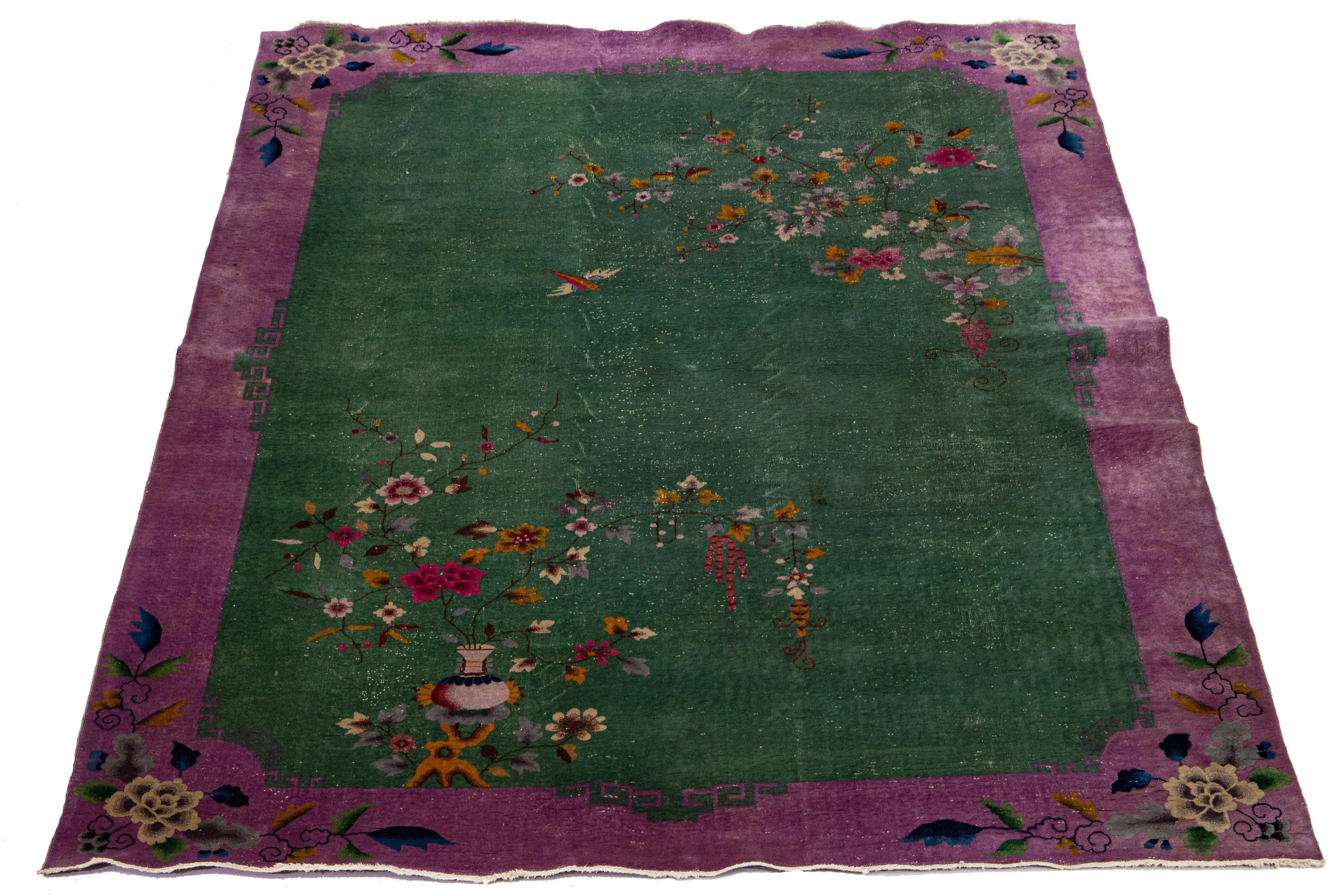 This hand-knotted antique Chinese Art Deco rug features a green field with a multicolored floral design and a purple wool frame. The elegant and sophisticated Chinese floral pattern makes it a classic.

This rug measures 9'11