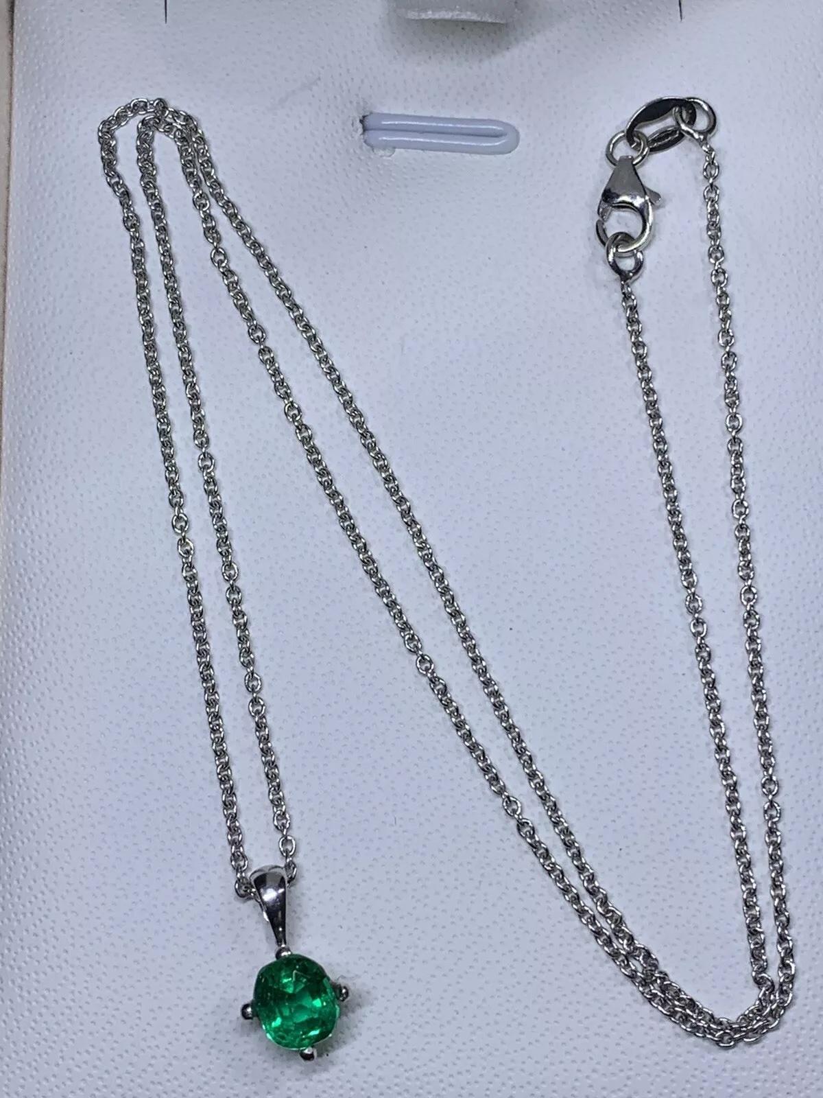 Ce magnifique collier pendentif est orné d'une superbe émeraude colombienne de 0,65ct, sertie dans un solitaire classique. Le pendentif rond est en or blanc 18ct et est rehaussé d'une pierre secondaire en émeraude de Colombie. Le collier est