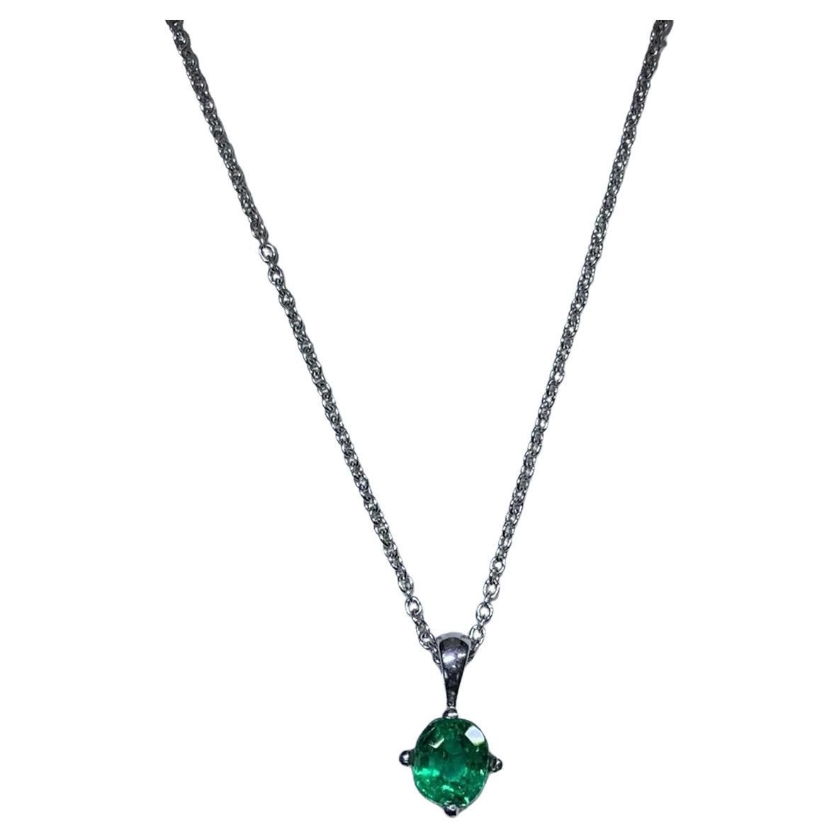 Green Colombian emerald round shaped solitaire pendant in 18k white gold.