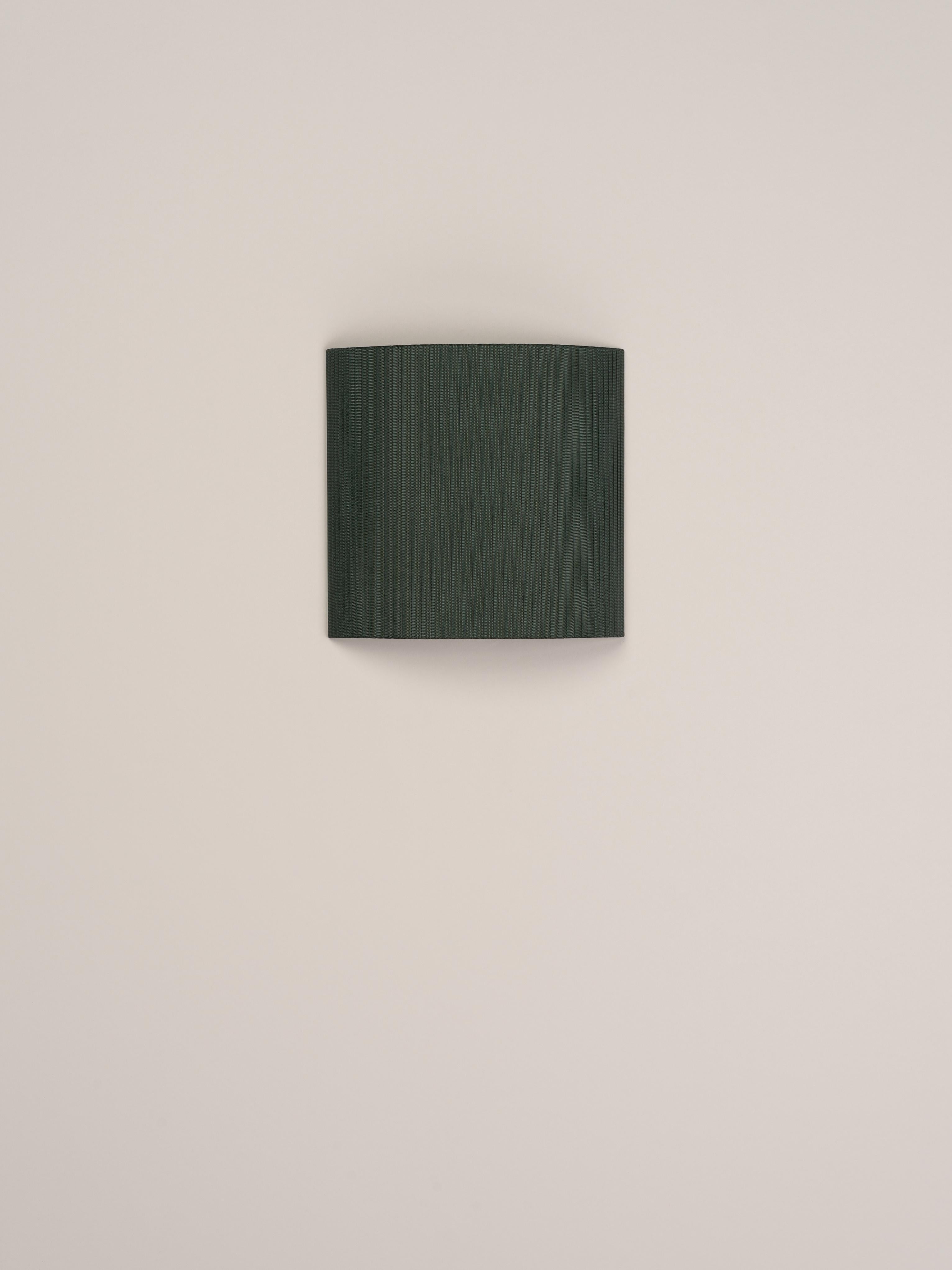 Green Comodín Cuadrado wall lamp by Santa & Cole
Dimensions: D 31 x W 13 x H 30 cm
Materials: Metal, ribbon.

This minimalist wall lamp humanises neutral spaces with its colourful and functional sobriety. The shade is fondly hand-ribboned, piece