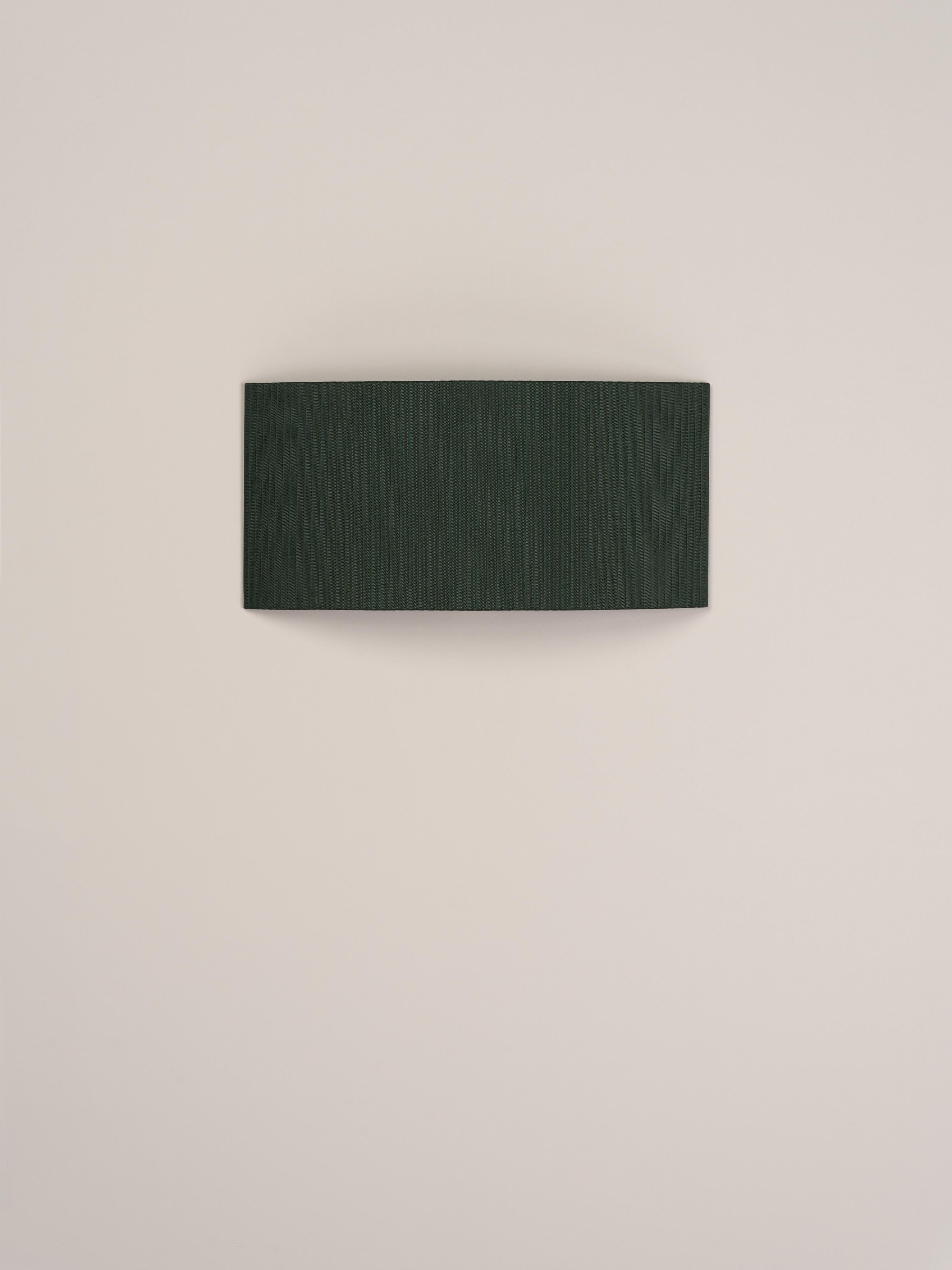 Green Comodín rectangular wall lamp by Santa & Cole
Dimensions: D 50 x W 13 x H 24 cm
Materials: Metal, ribbon.

This minimalist wall lamp humanises neutral spaces with its colourful and functional sobriety. The shade is fondly hand-ribboned,