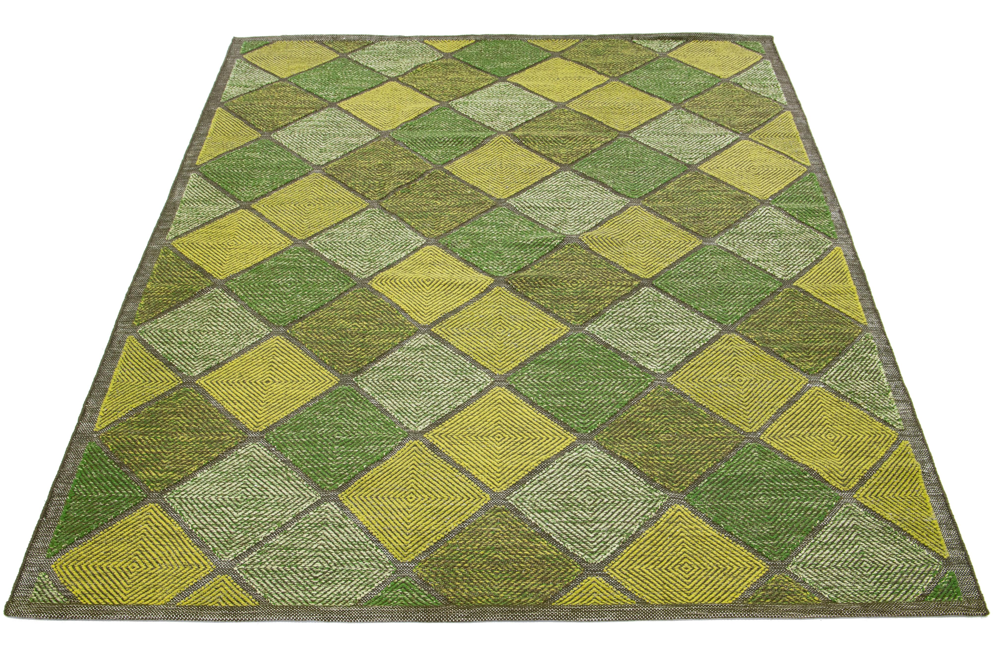 This flatweave rug features a modern Swedish design with a green base. Beige, light green and yellow geometric patterns complement it throughout the design.

 This rug measures 8'11