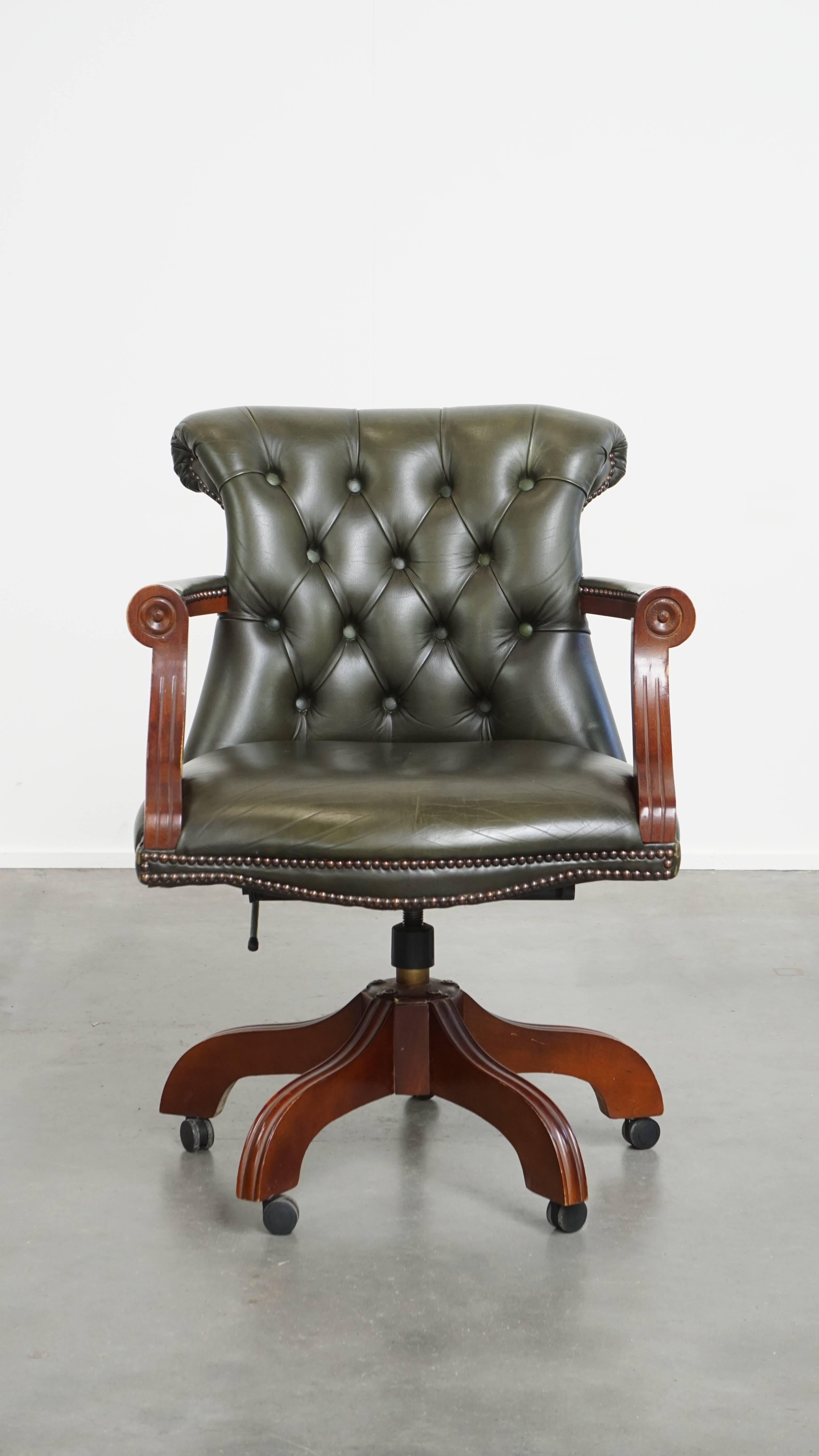 Offered: this timeless green cowhide leather Chesterfield office chair in English style, set on casters and finished with decorative studs. This charming green leather and wooden Chesterfield office chair in English style suits nearly any interior