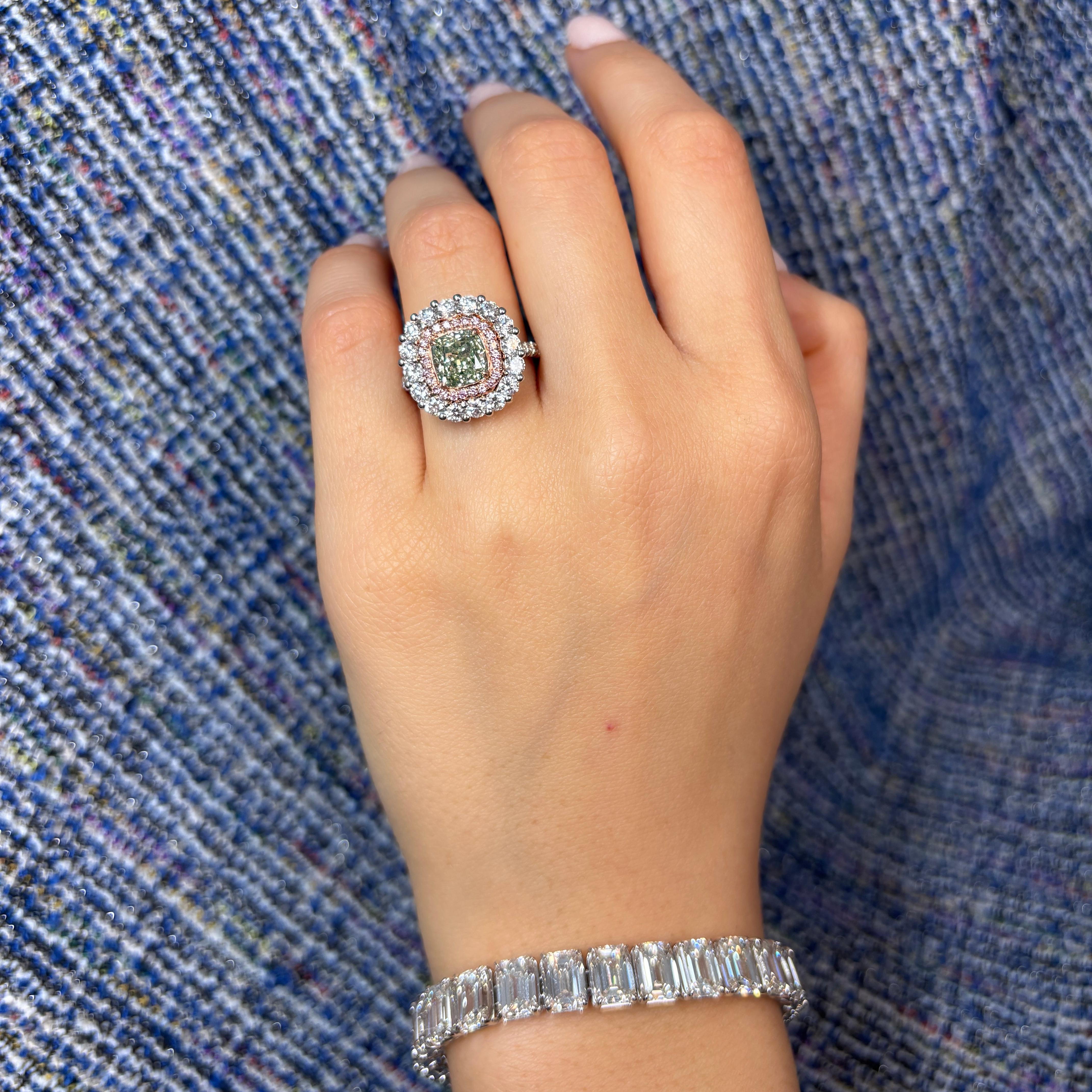 A true celebration of rare beauty, this stunning ring features a mesmerizing 1.99 carat Fancy Greyish Greenish Yellow cushion cut diamond at its center. Its enchanting hue is accentuated by a delicate halo of natural pink and white diamonds, adding