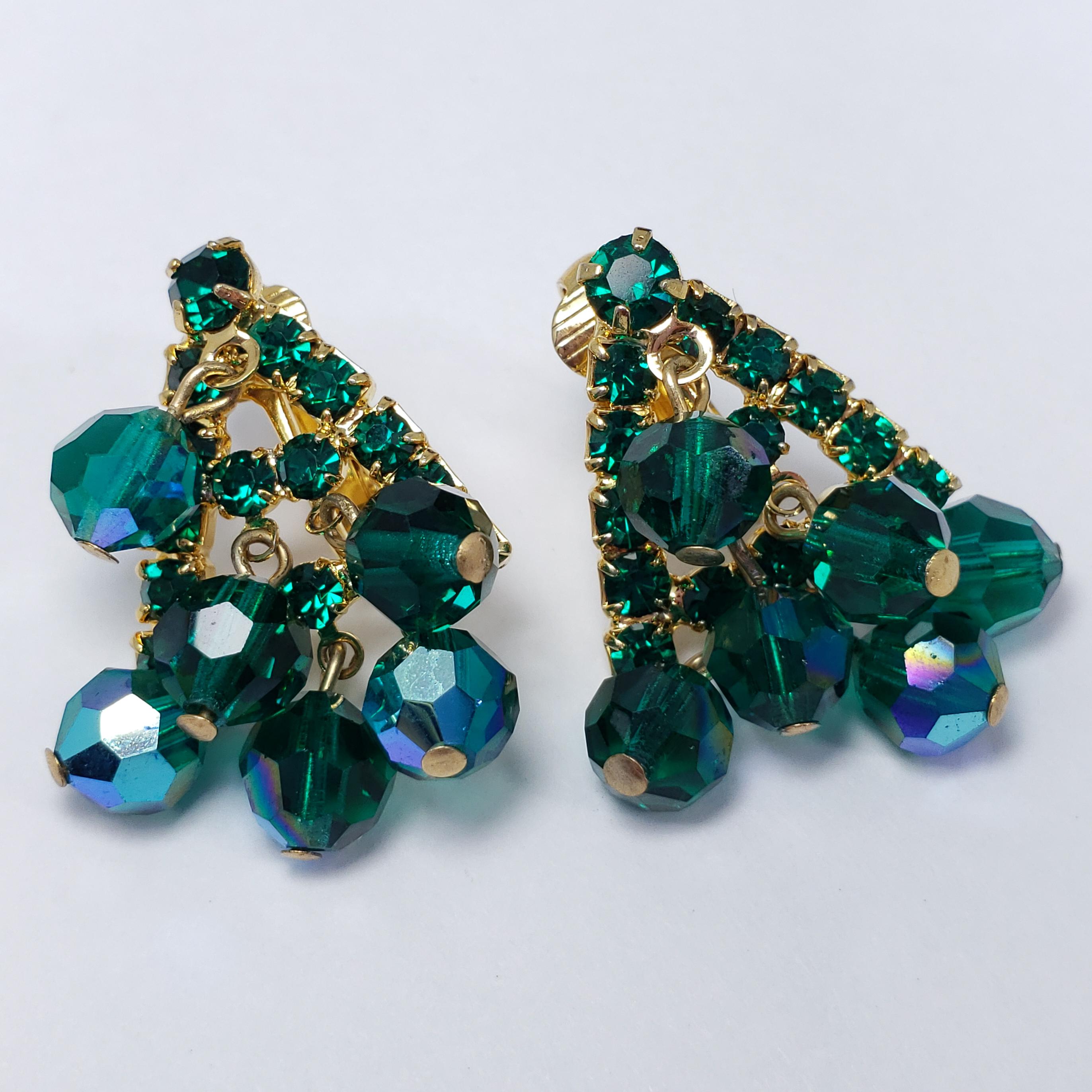 A pair of extravagant crystal cluster clip-on earrings by an unknown mid-1900s designer. Each earring features a triangular gold-tone metal setting, accented with prong-set crystals and dangling beads. Clip on backs. Stylish!