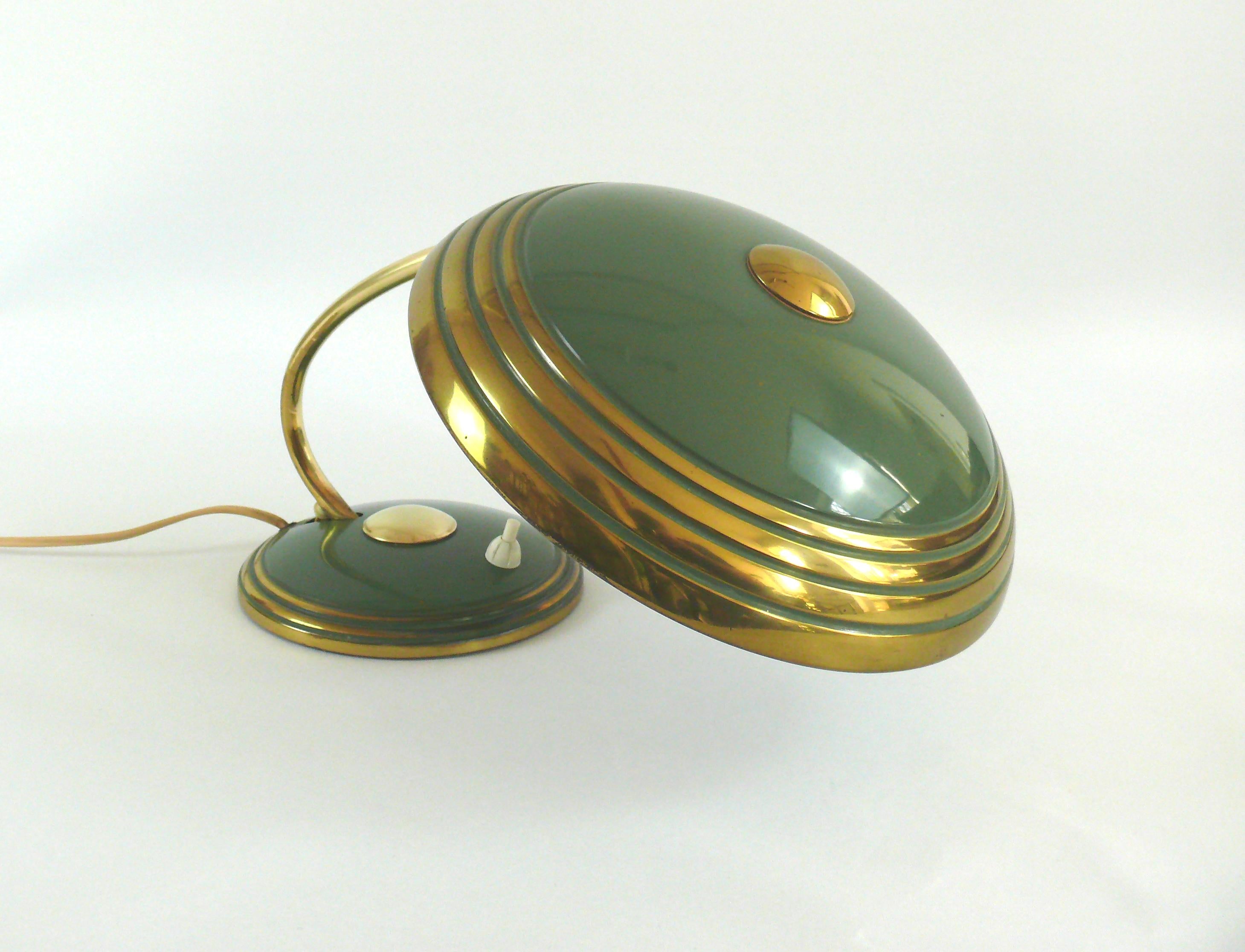 Massive Schreibtischlampe in Grün mit Messingflächen aus den 1950er Jahren. Die Leuchte wird von HELO Leuchten, Deutschland, hergestellt. Der Kontrast zwischen den grünen Flächen und den Messingteilen verleiht der Lampe eine edle Ruhe. Stilistisch