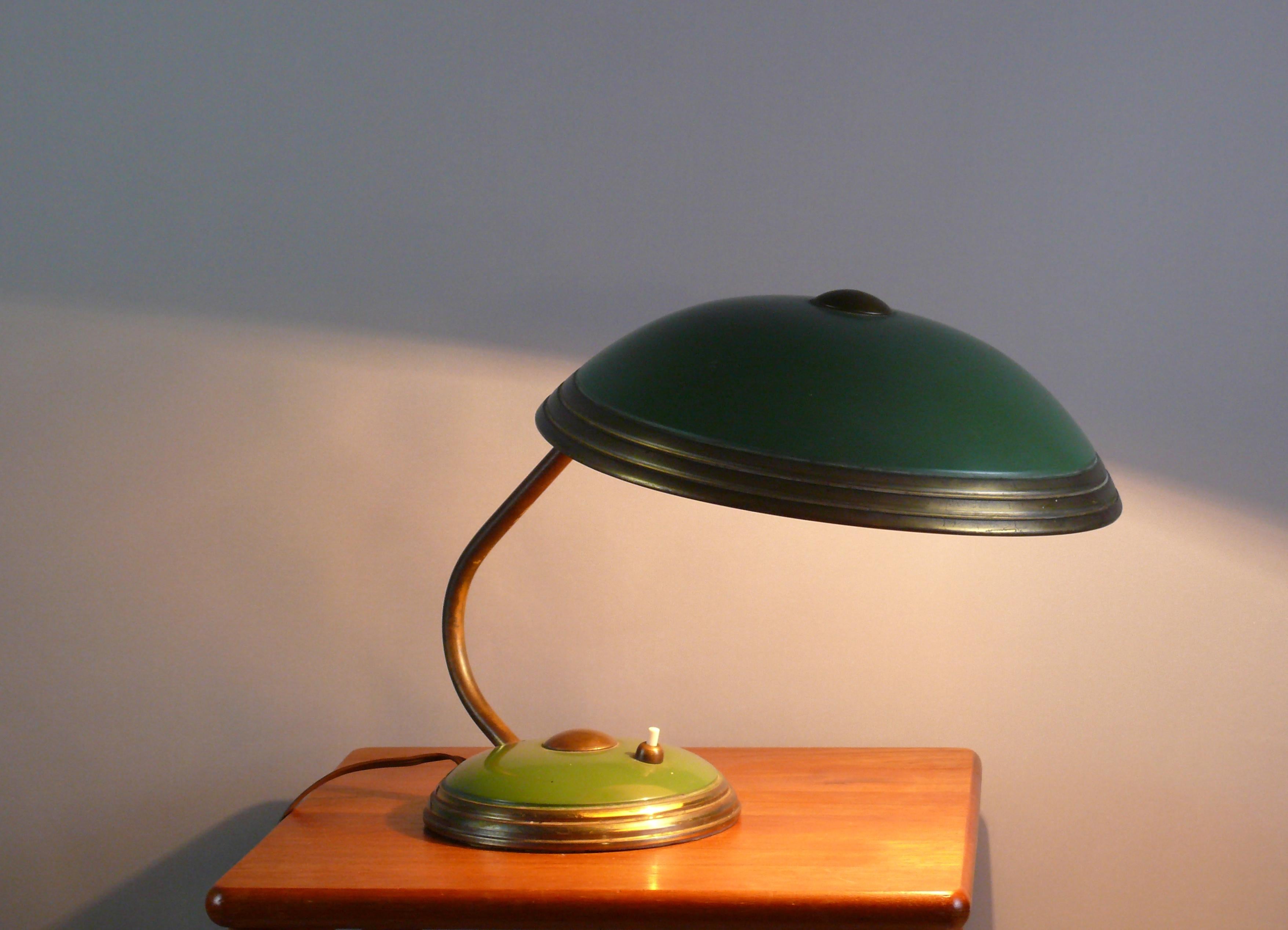 Helo-Tischleuchte im originalen, unpolierten Zustand, ein zeitloser Klassiker aus den 1950er Jahren. Stilistisch lehnt sich das Design der Leuchte an die Bauhaus-Zeit an. Der Lampenschirm lässt sich mit einem Kugelgelenk vielfältig verstellen. Die