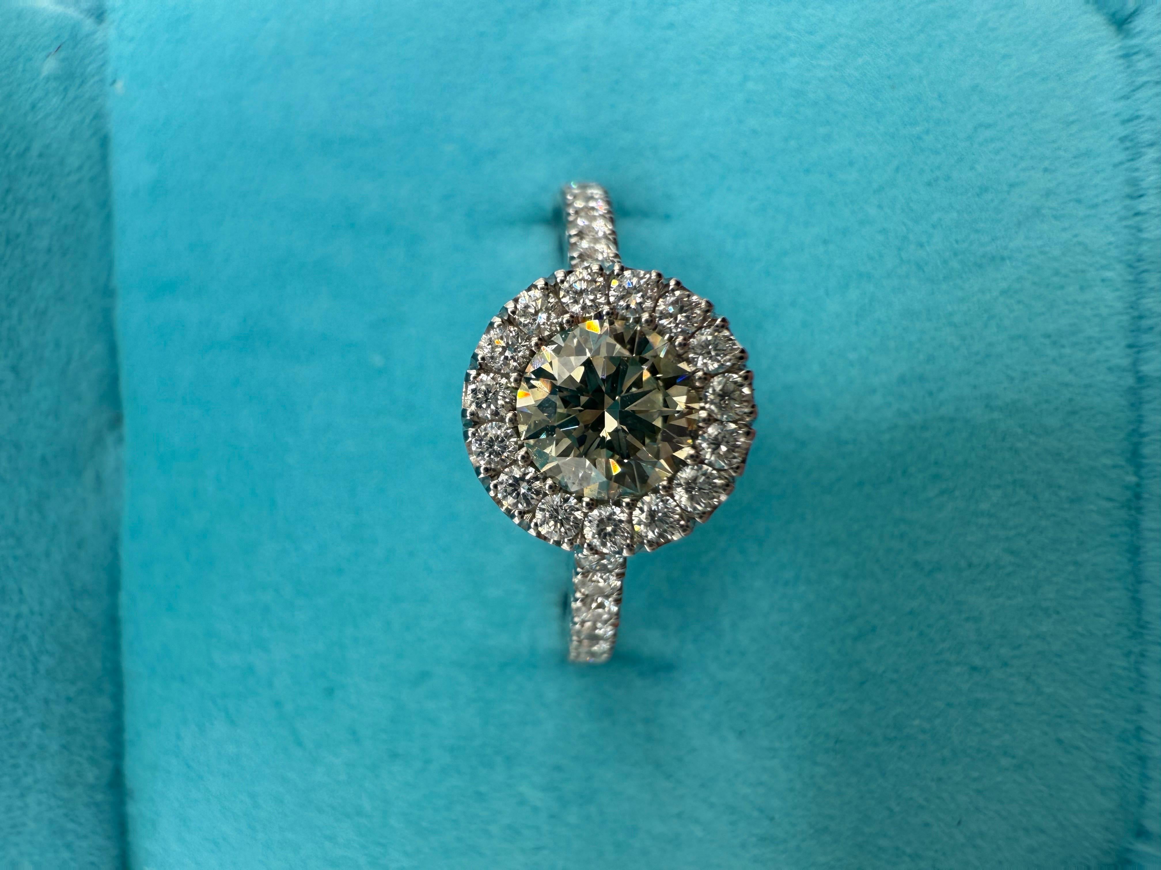 Stunning rare natural fancy light yellowish green center accompanied by a halo of diamonds, all diamonds are VS-SI clarity and F-G colors. The center is 0.45 carats. This is a rare diamond ring to come across as the center is a natural color earth