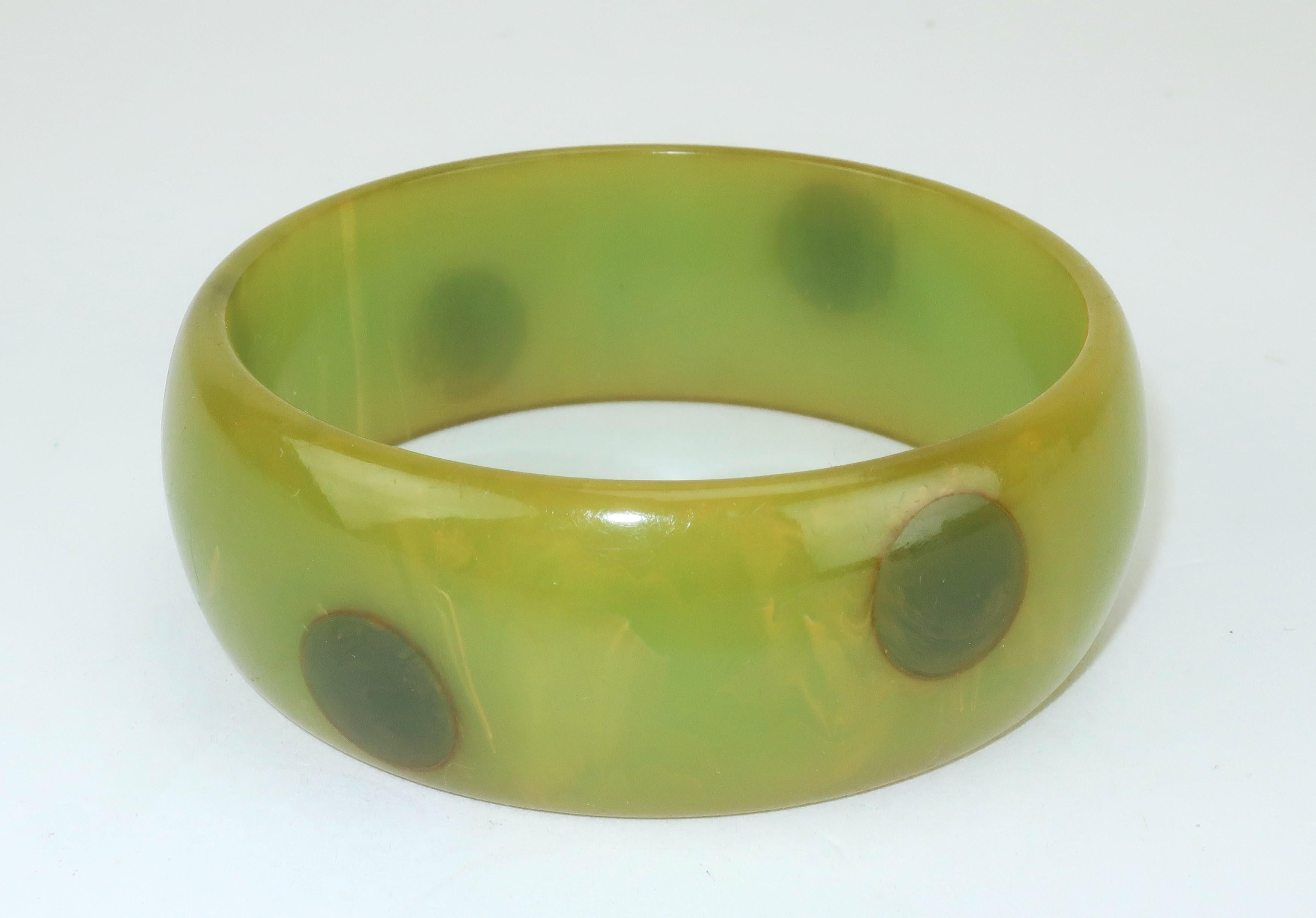 1940's bakelite bangle bracelet in shades of green ranging from olive to forest with a marbleized effect incorporating a touch of yellow.  The bracelet is decorated with a polka dot pattern similar to 'confetti' or 'gum drop' styles.  It is fun to