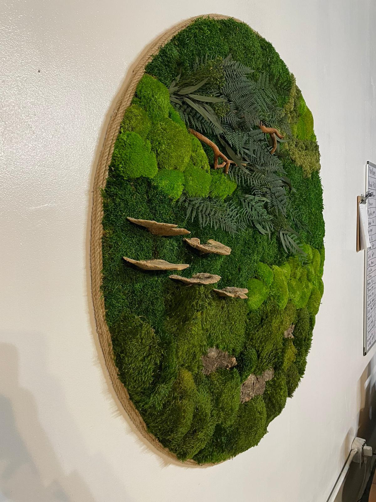 This piece was designed by Serkan Yapicilar, Lead Designer for Naturalist Interiors out of his Hoboken, NJ design studio.

It is made of natural preserved plants that are completely maintenance free. They do not have soil beneath their roots, nor