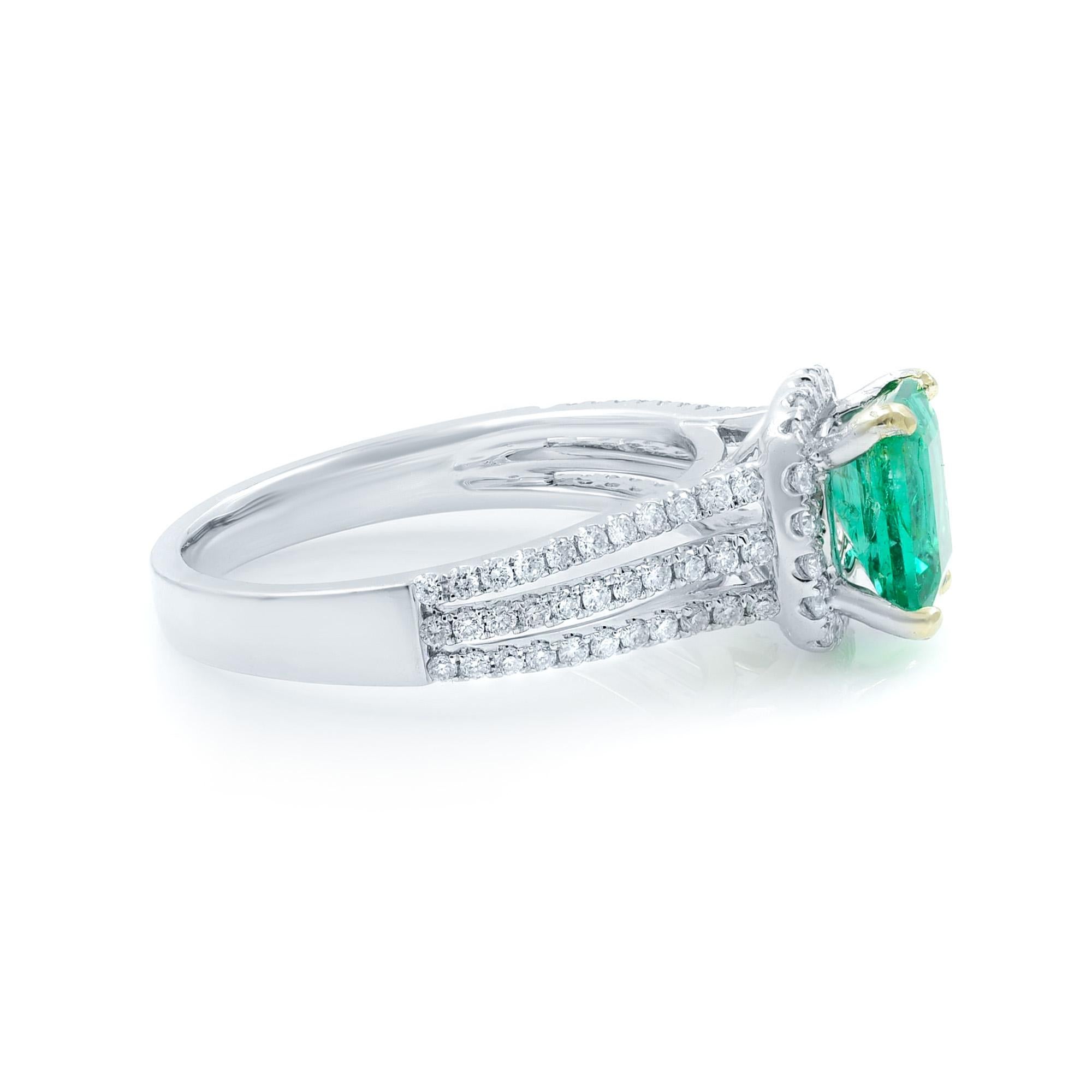 This gorgeous engagement ring features a Colombian emerald stone with a delicate diamond pave halo design. The ring is crafted in 18k white gold with a triple splint shank setting. The total carat weight of Colombian emerald is 1.00 and diamonds is