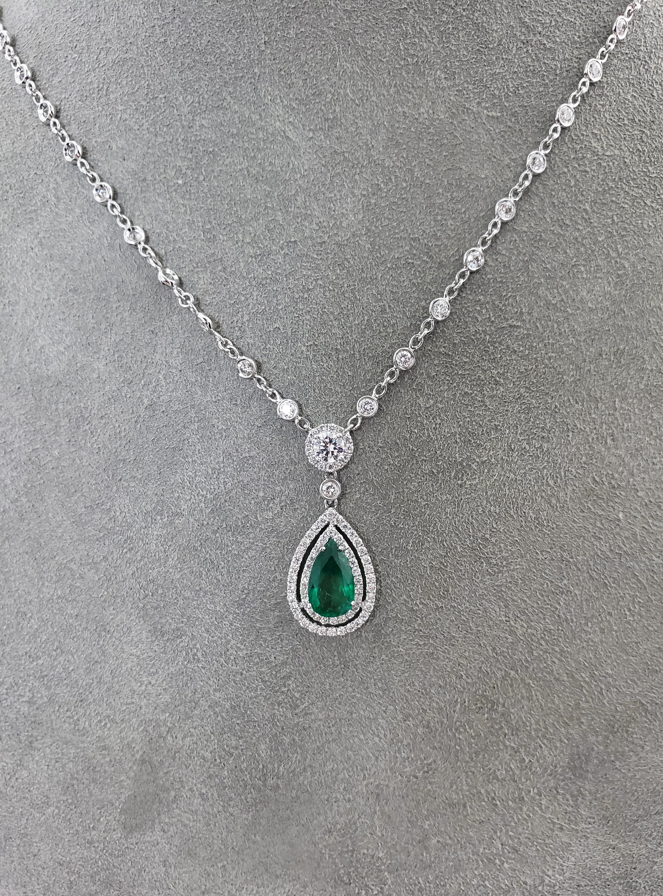 The pendant showcases a 1.28 carat pear shaped green emerald center stone surrounded by two rows of dazzling diamonds. Suspended on a round diamond that is attached to a diamonds by the yard chain. Total weight of the diamonds 2.51 carats. Crafted