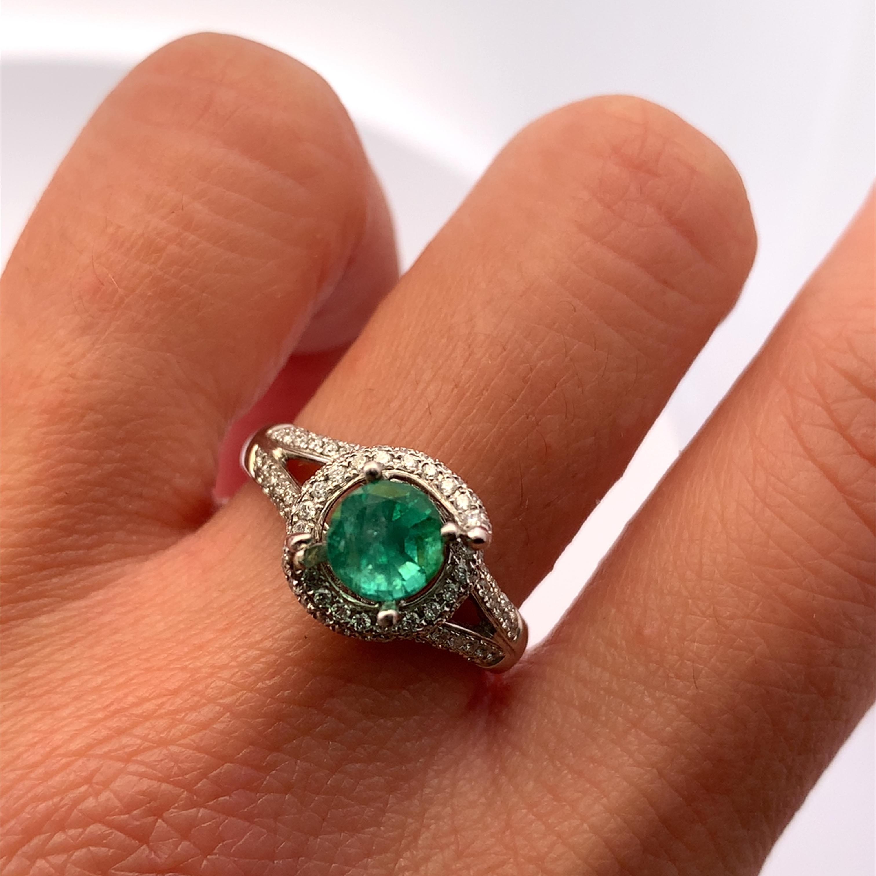 Discover the allure of this stunning green emerald and diamond halo twisted twirl ring, featuring a vibrant vivid green gemstone and diamonds that captures the essence of elegance. Crafted in 18k white gold with precision, the sleek band complements