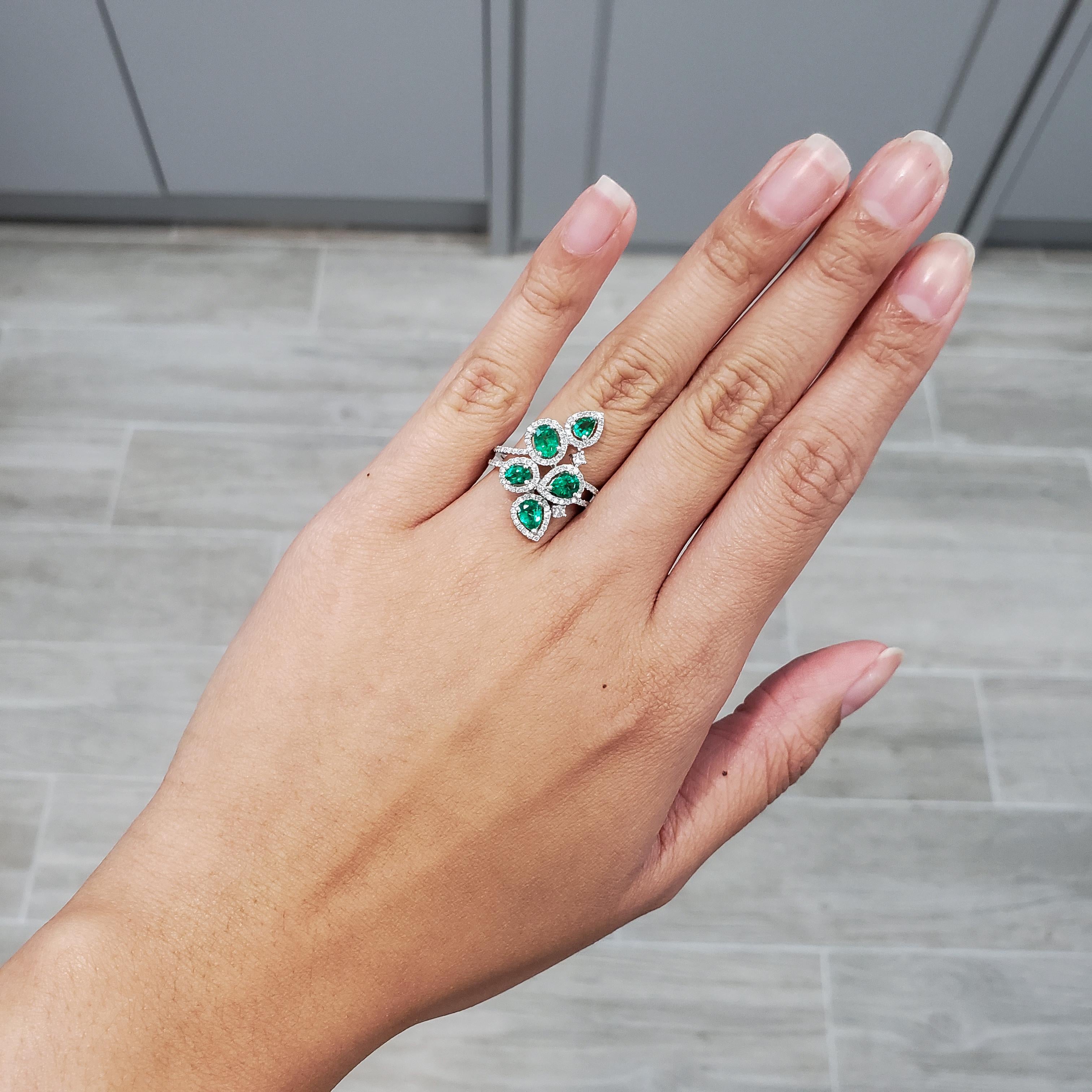 A fashionable and color-rich ring showcasing a cluster of green emeralds, each surrounded by a brilliant diamond halo. Set in a double row shank accented with more diamonds. Emeralds weigh 1.19 carats total; diamonds weigh 0.57 carats total. Made in