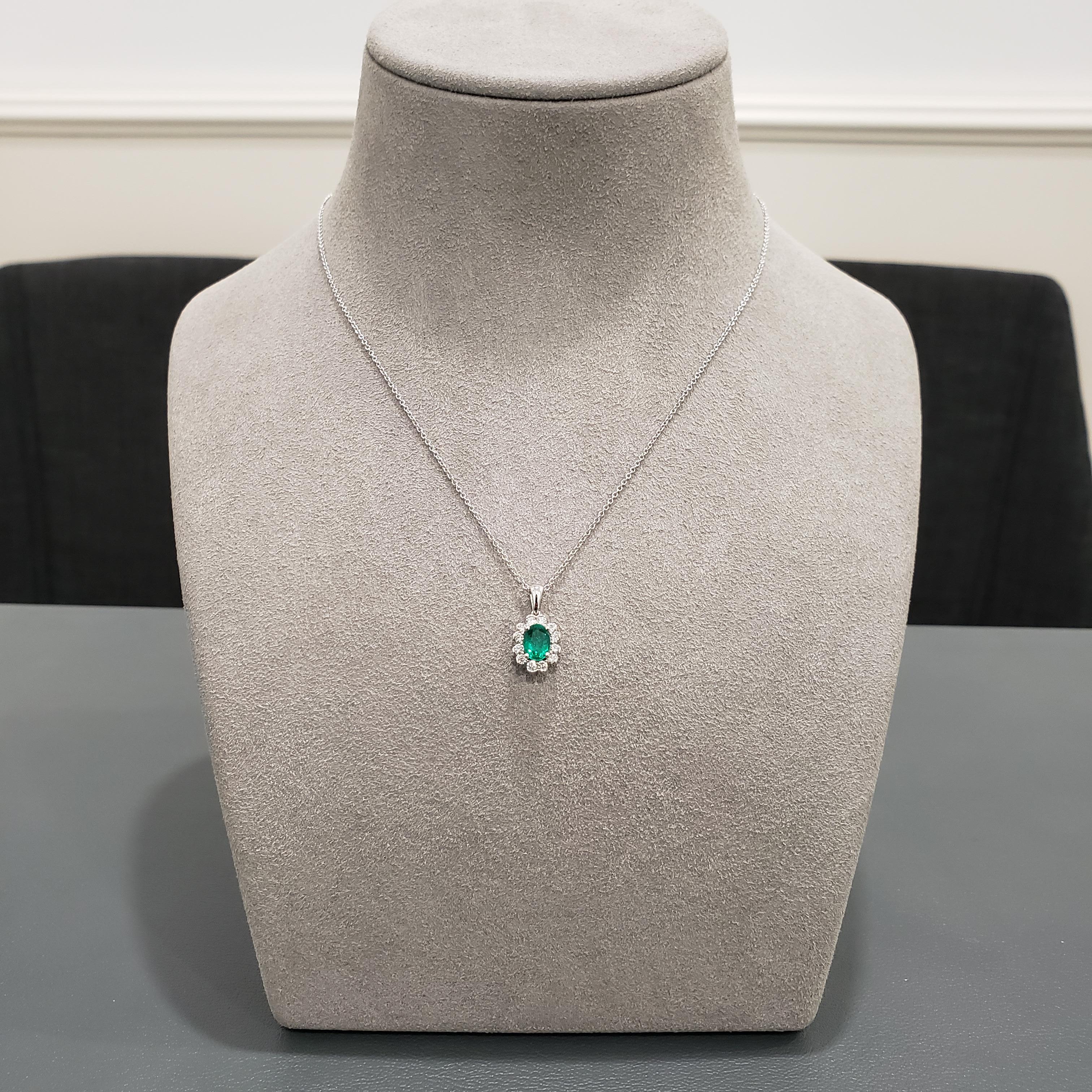This pendant necklace of floral motif features a 0.71 carat oval cut green emerald, surrounded by a single row of round brilliant diamonds in a halo design weighing 0.30 carats total. Made in 18K white gold.

Style available in different price