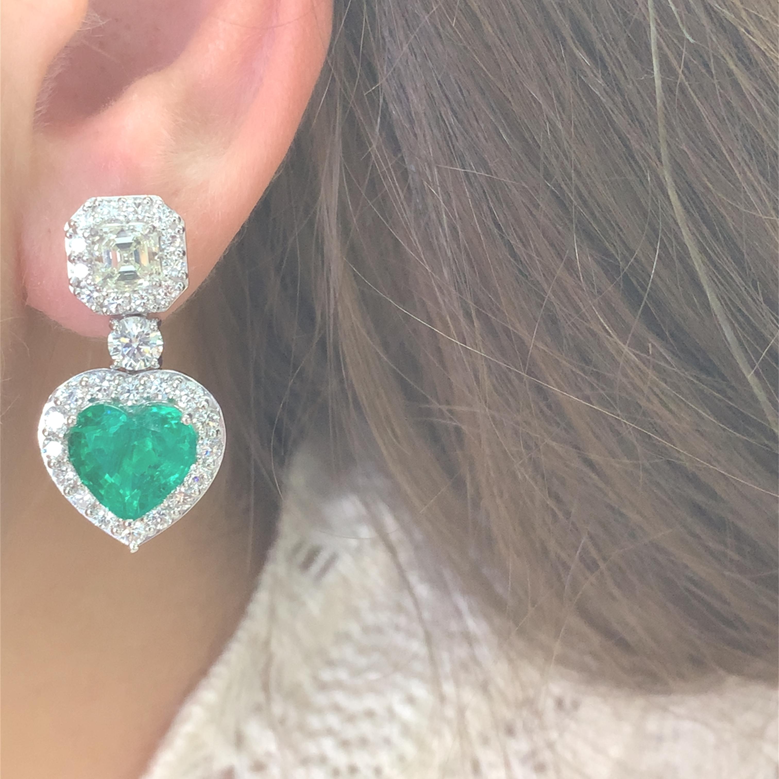 These stunning heart-shaped green Zambian origin emerald earrings are a perfect blend of elegance and sophistication. Surrounded by a halo of sparkling diamonds, they capture the light beautifully, making them an ideal accessory for any special