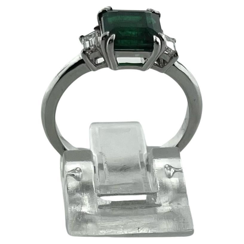 This Cushion Green Emerald weighs 1.62cts and is adorned by two straight baguette diamonds on each side (0.28ctw) all set in 18K White Gold. 

The green emerald is clean to the eye with slight inclusions under magnifier. 
 
The ring can be resized