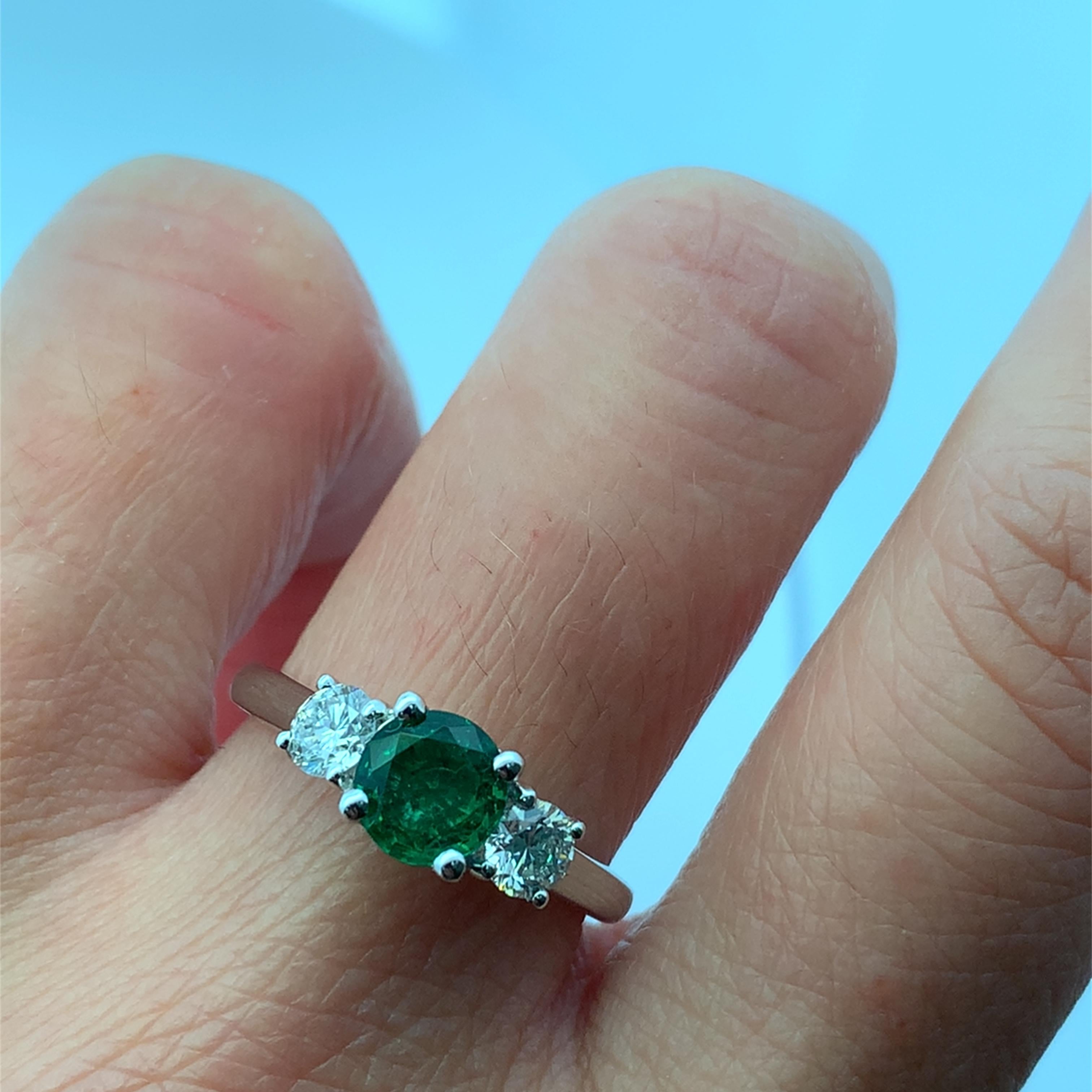 Este impresionante anillo presenta una vibrante pieza central de esmeralda flanqueada por dos brillantes diamantes, creando un equilibrio perfecto de color y brillo. Elaborado con precisión, está diseñado para causar sensación en cualquier ocasión,