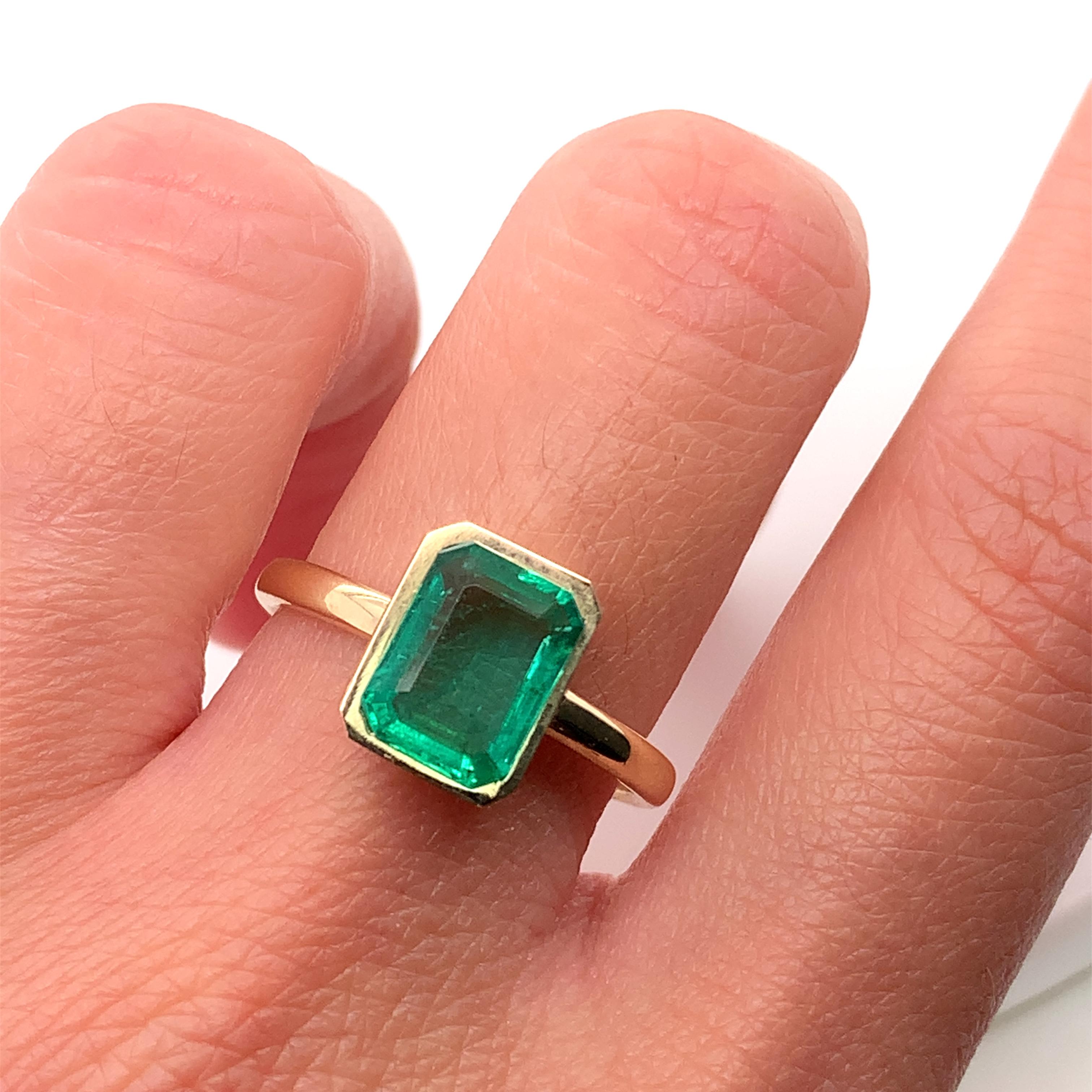 Adorn your loved one's finger with this stunning 1.38ct green emerald bezel engagement ring. Crafted from 18k yellow gold, this ring features a beautiful cushion-shaped main stone that is sure to catch the eye of anyone who sees it. The solitaire