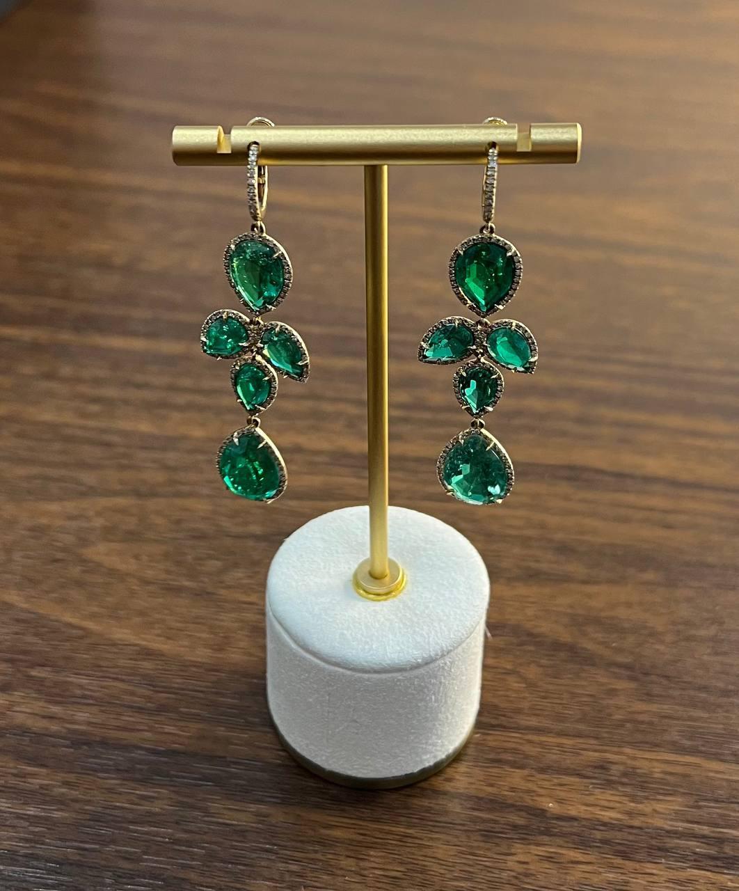 Estos exquisitos pendientes presentan vibrantes gemas verdes con un peso total en quilates primarios de 31,77. Cada piedra está elegantemente rodeada por 1,23 quilates de brillantes diamantes, que realzan su resplandor.

Fabricado en oro de 14