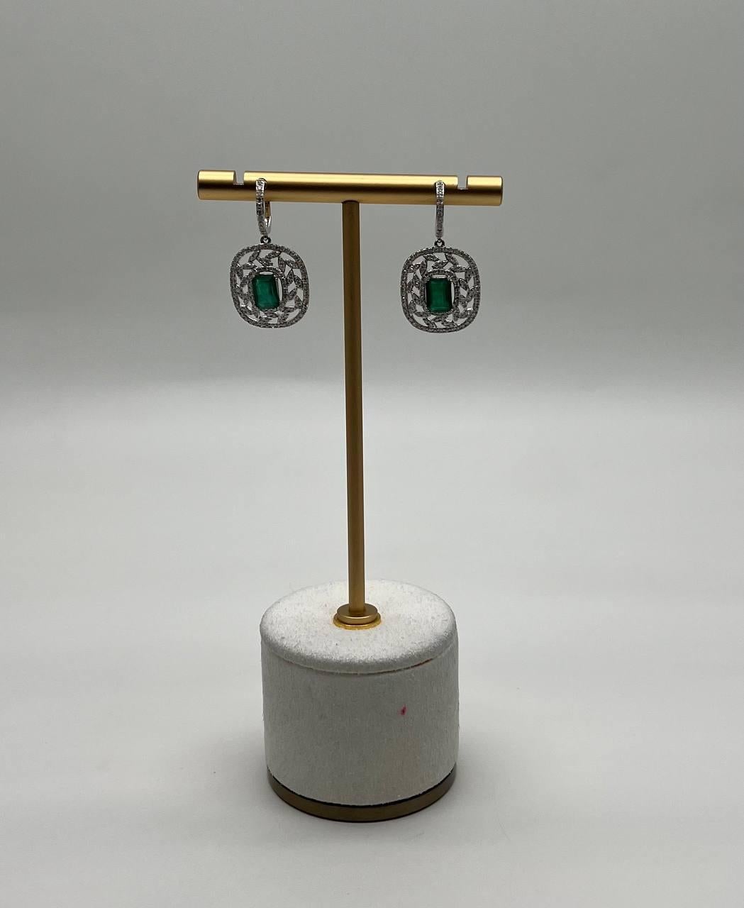 Questi sofisticati orecchini sono realizzati con bellezza e precisione.
Ogni orecchino presenta uno smeraldo verde rettangolare centrale, incastonato in un intricato disegno a traforo di diamanti a reticolo.
La cornice circostante è ornata da