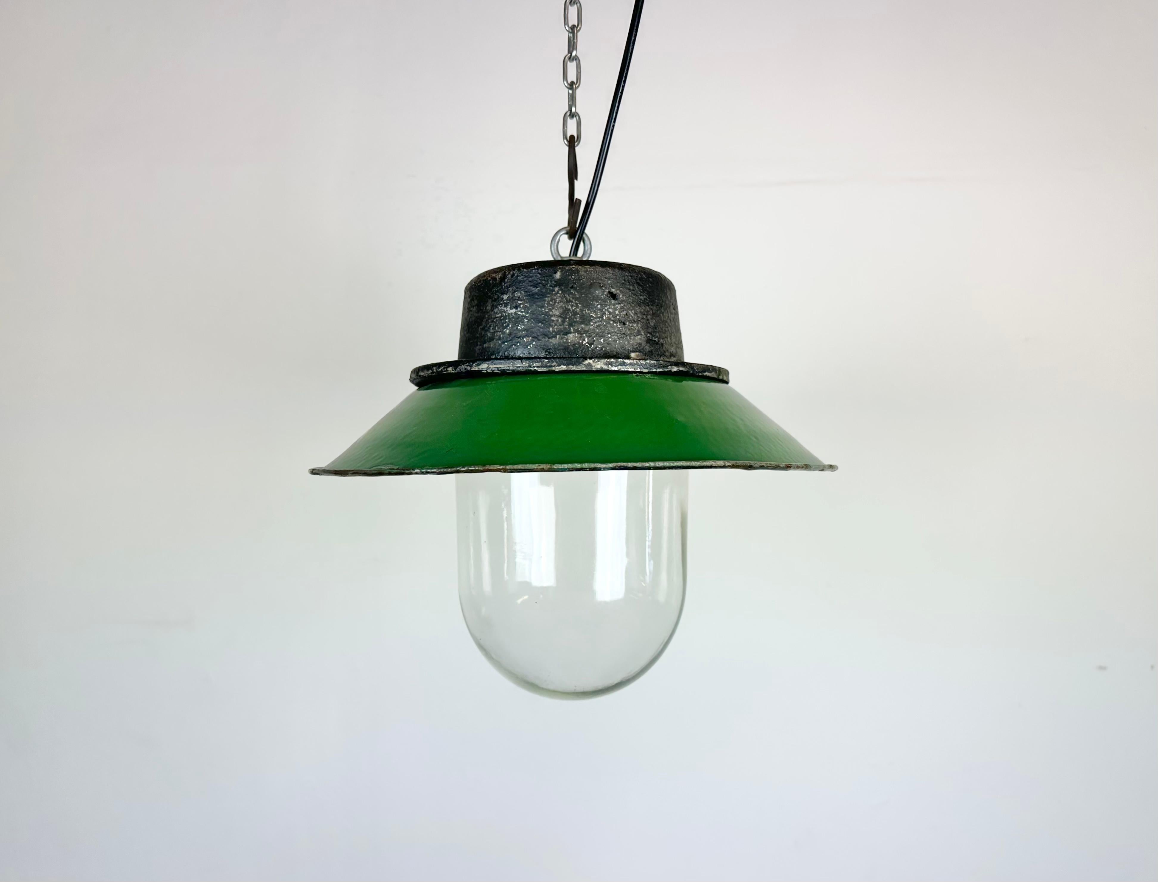 Industrial hanging lamp manufactured in Poland during the 1960s. It features a green enamel shade with white enamel interior, a cast iron top and a glass cover. The porcelain socket requires E 27/ E26 lightbulbs .New wire. The weight of the lamp is