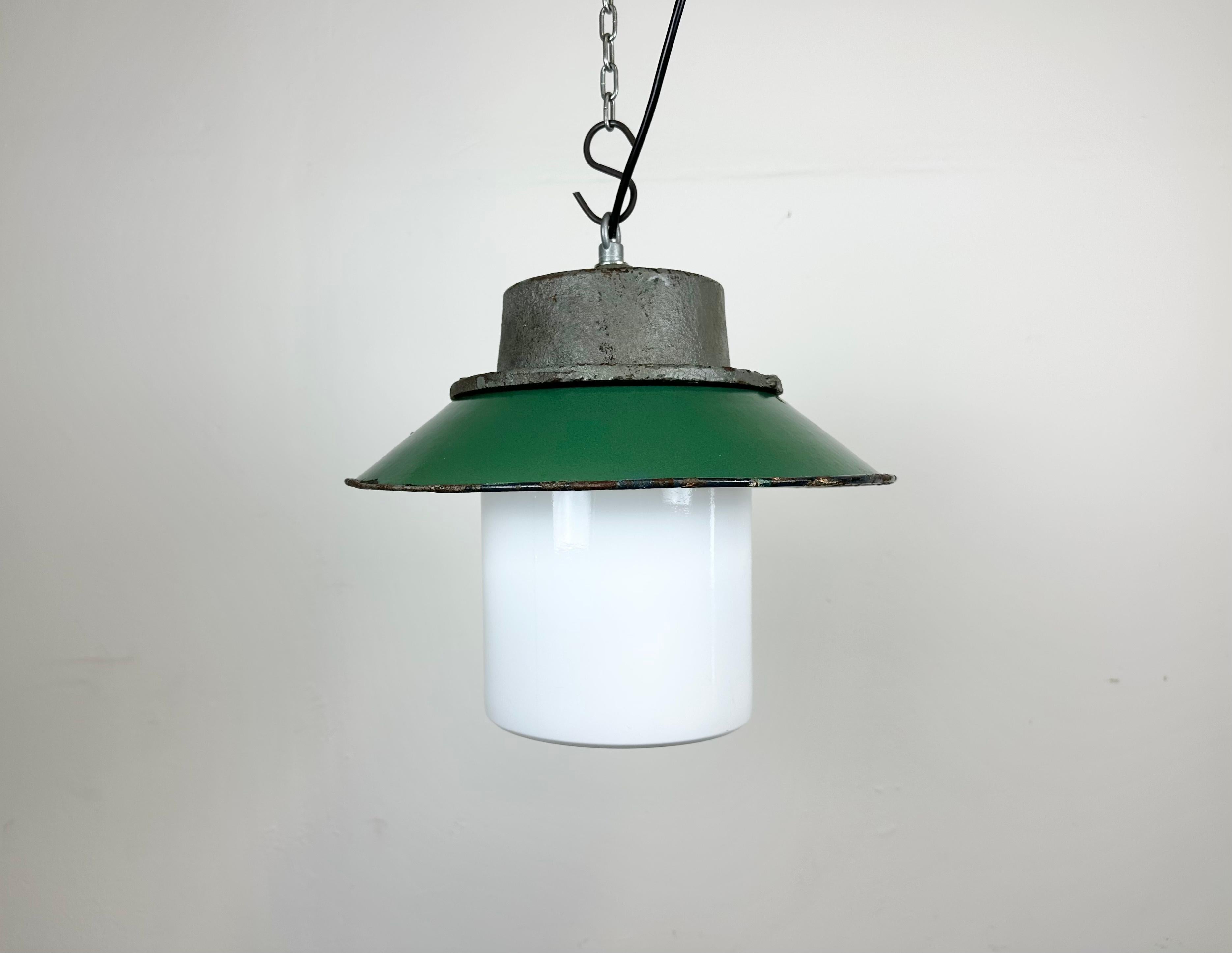 Industrial hanging lamp manufactured in Poland during the 1960s. It features a green enamel shade with white enamel interior, a grey cast iron top and a milk glass cover. The porcelain socket requires E 27/ E26 lightbulbs .New wire. The weight of